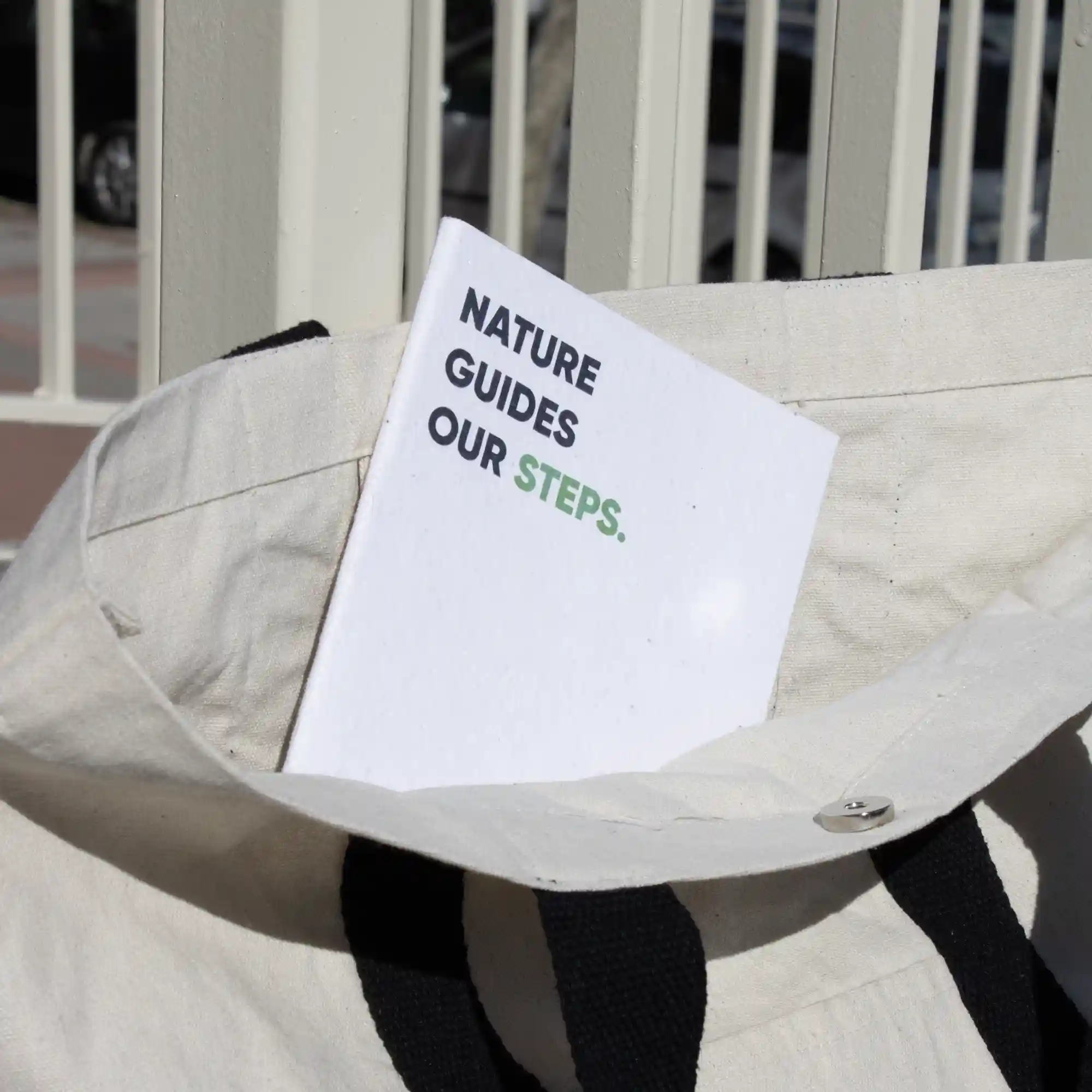 Cuaderno plantable blanco personalizado con el texto 'Nature guides our steps' dentro de una bolsa de algodón blanca