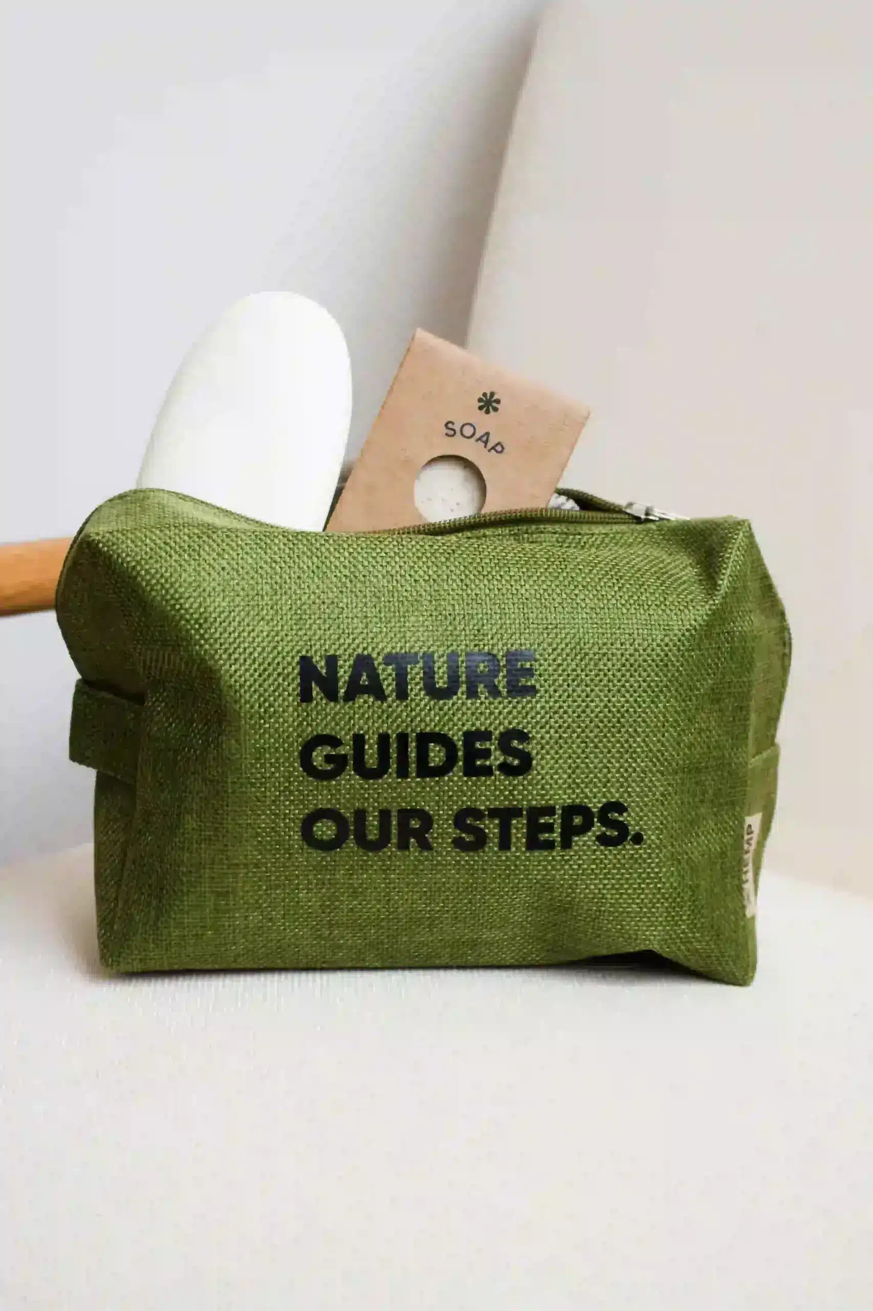 Jabones dentro de un neceser verde personalizado colocado sobre una butaca blanca
