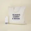 Bolsa de algodón beige personalizada con el texto 'Always carry a book' junto a un marcapáginas de papel plantable personalizado