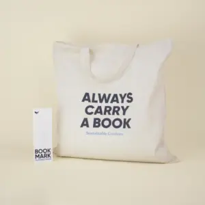 Bolsa de algodón beige personalizada con el texto 'Always carry a book' junto a un marcapáginas de papel plantable personalizado