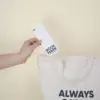Mano metiendo un marcapáginas de papel plantable personalizado en una bolsa de algodón beige