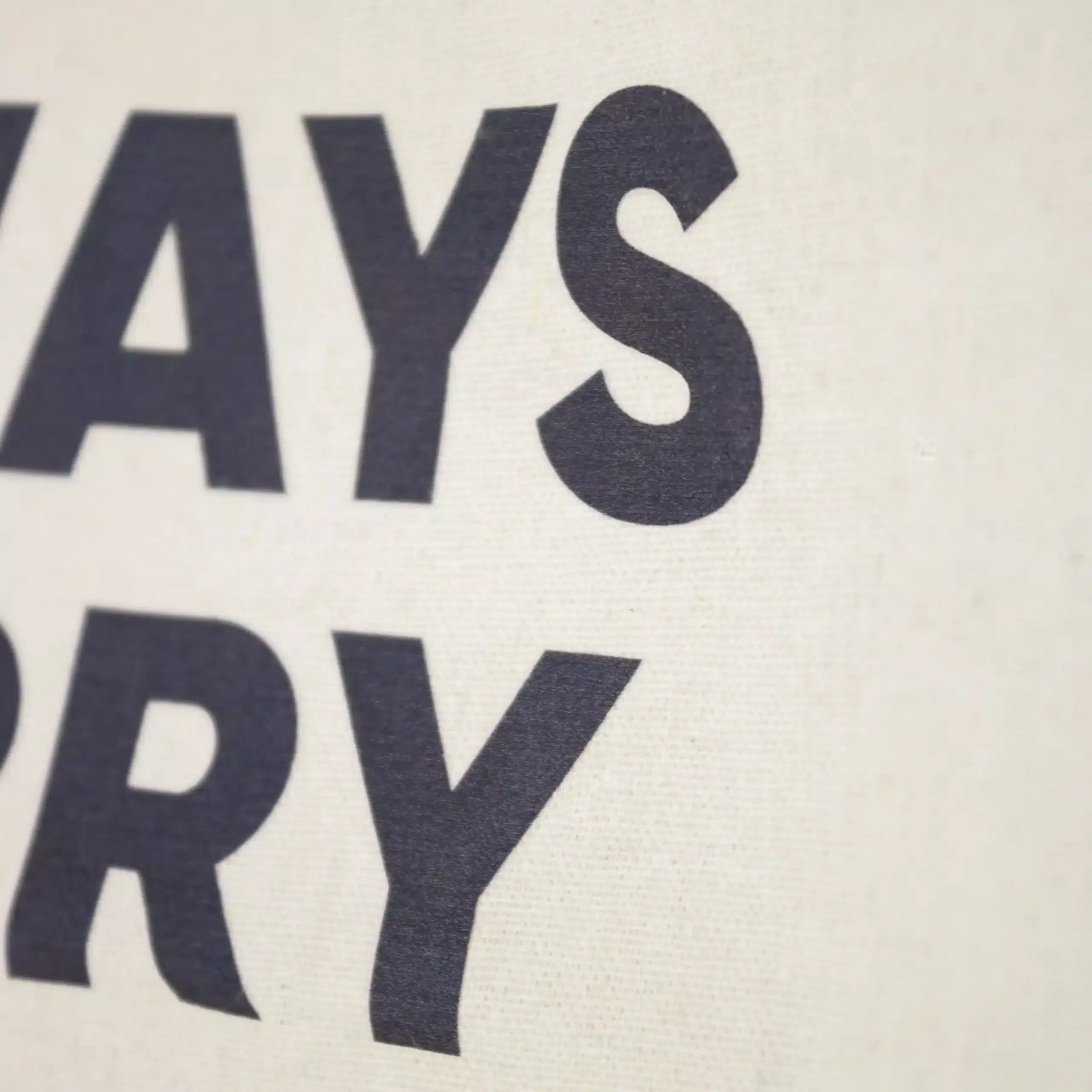 Detalle de impresión de una bolsa de algodón beige personalizada con textos en azul