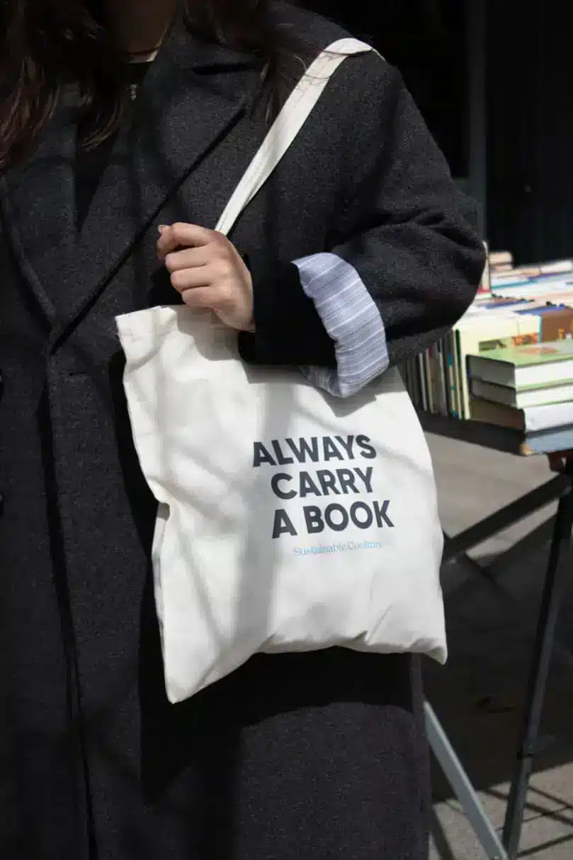 Chico llevando una bolsa de algodón beige personalizada con el texto 'Always carry a book'
