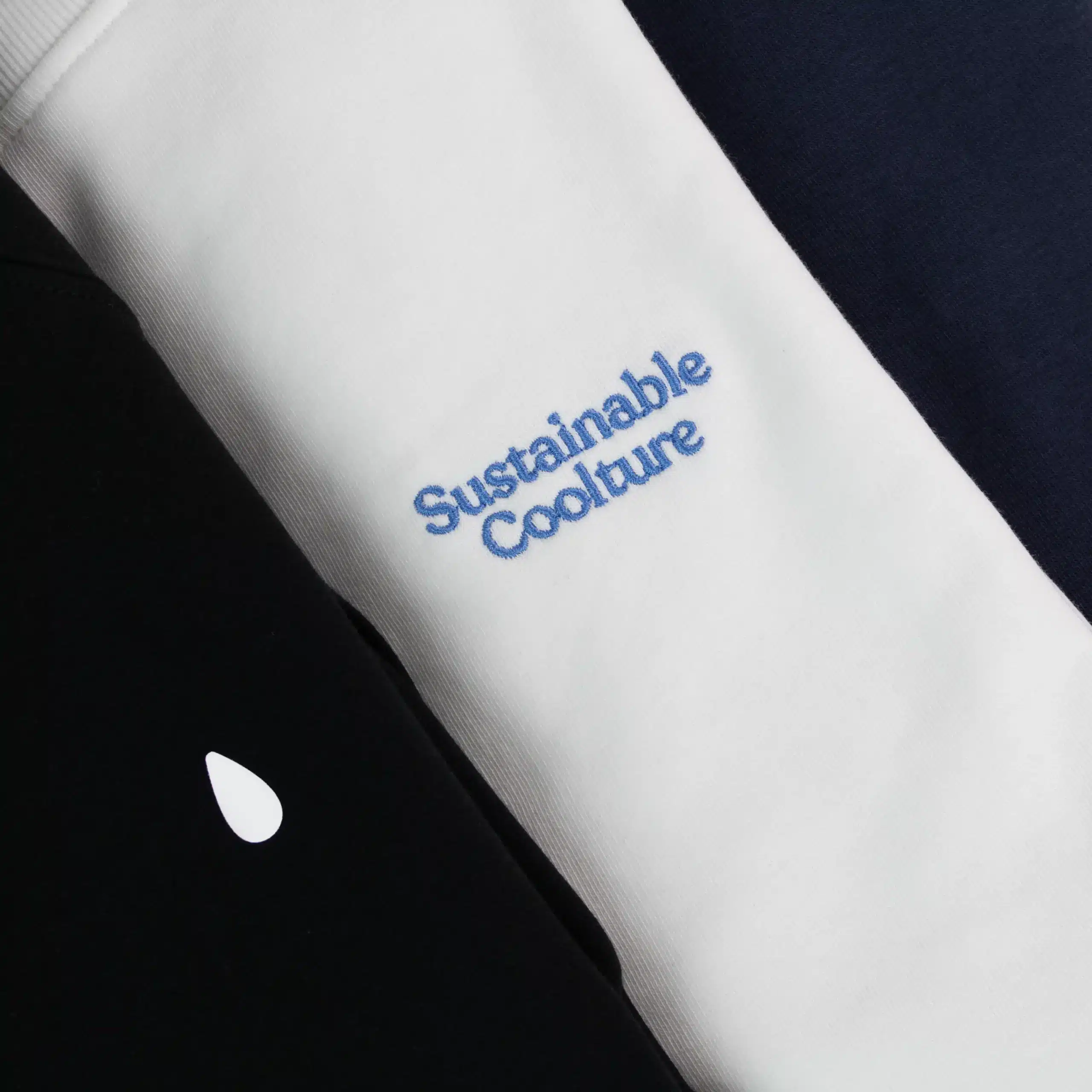 Detalle del texto 'sustainable coolture' bordado en una sudadera con capucha blanca