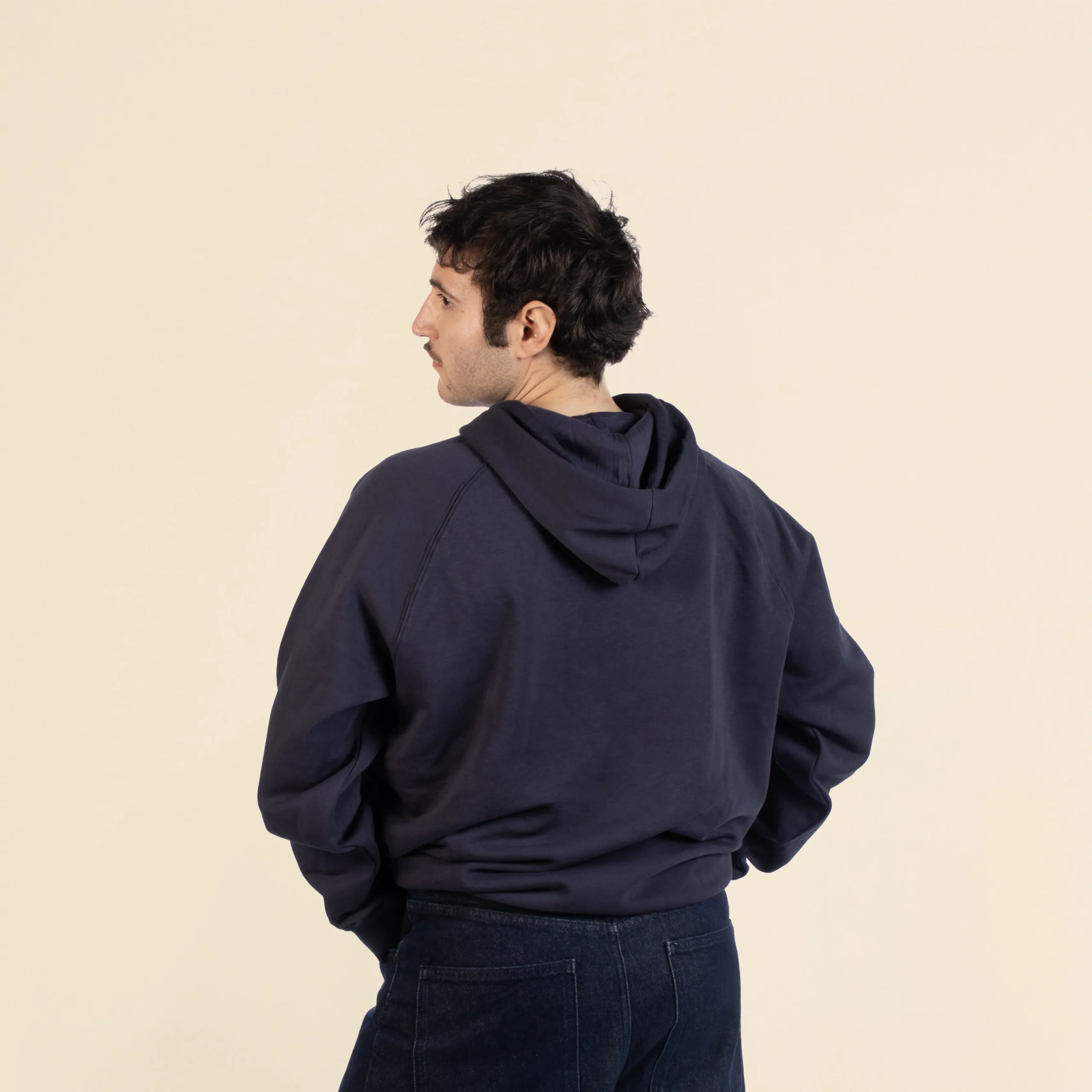 Chico moreno de espaldas llevando jeans y una sudadera con capucha azul personalizada