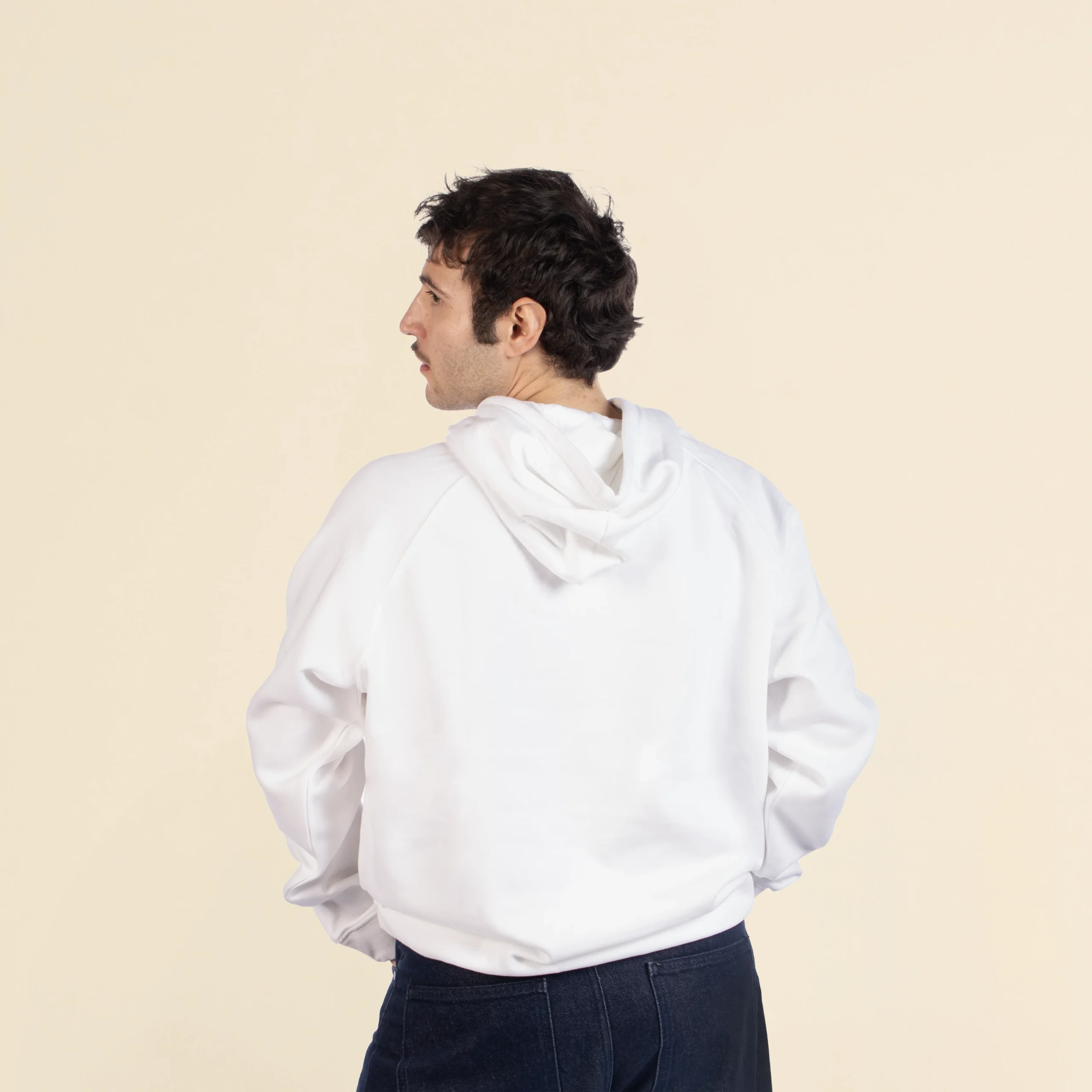 Chico moreno de espaldas llevando jeans y una sudadera blanca con capucha personalizada