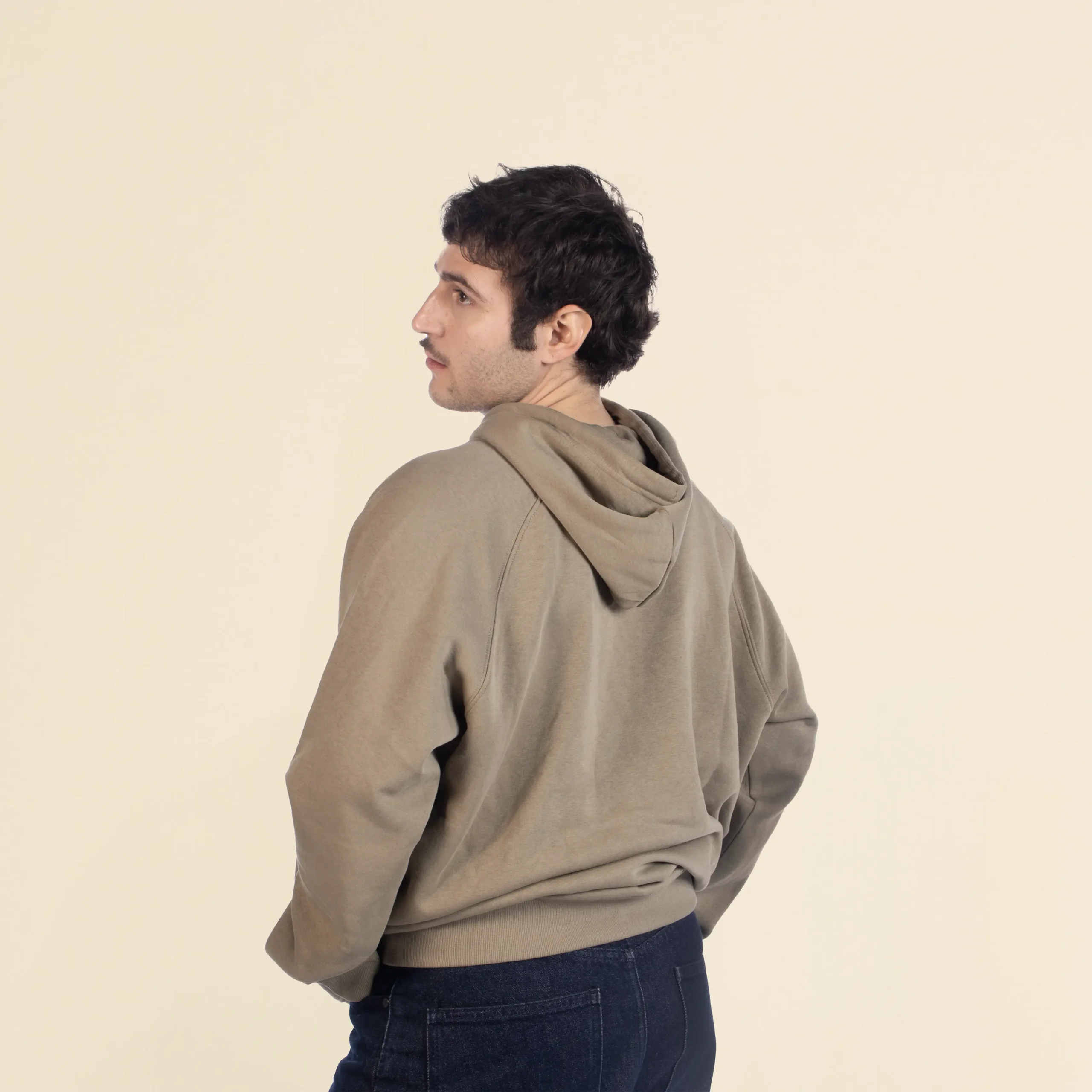 Chico moreno de espaldas llevando jeans y una sudadera verde con capucha personalizada