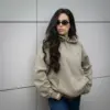 Chica morena con gafas de sol, llevando jeans y una sudadera verde personalizada