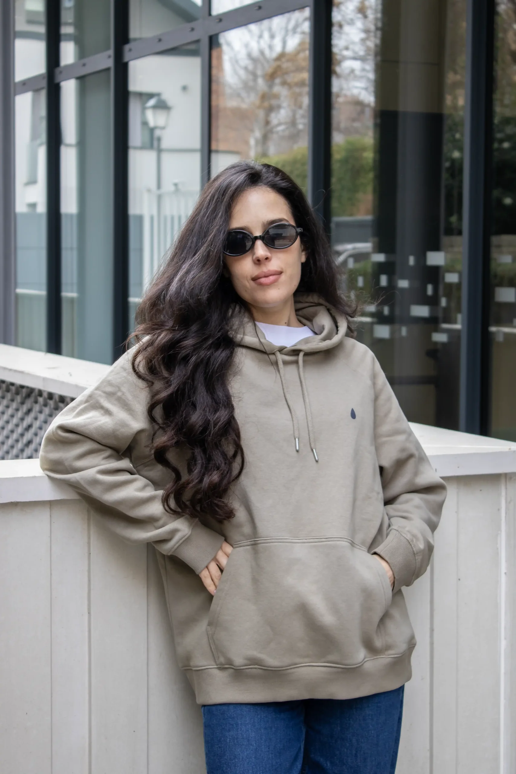 Chica morena con gafas de sol, llevando jeans y una sudadera verde personalizada