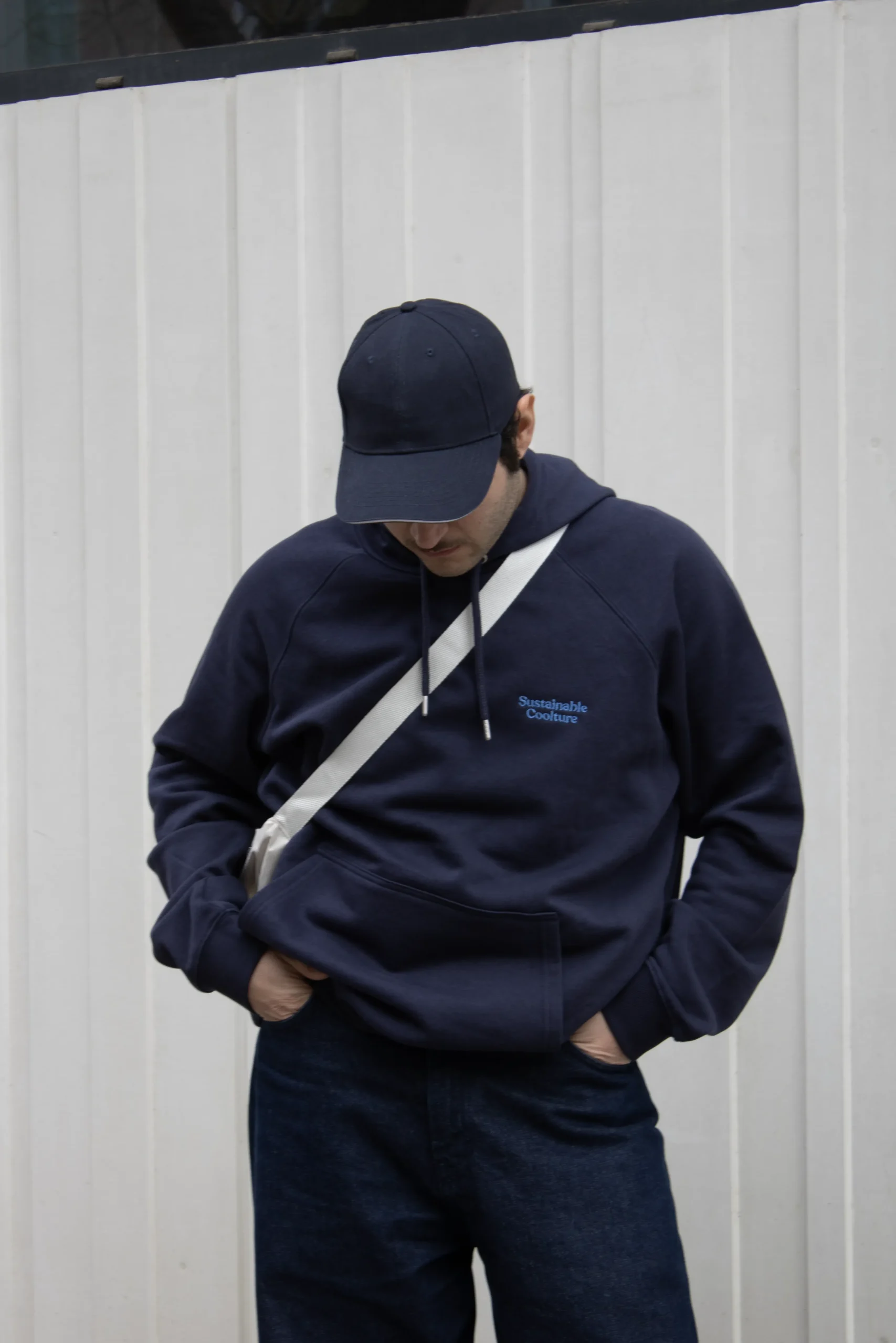 Chico moreno con una gorra azul llevando jeans y una sudadera con capucha azul personalizada