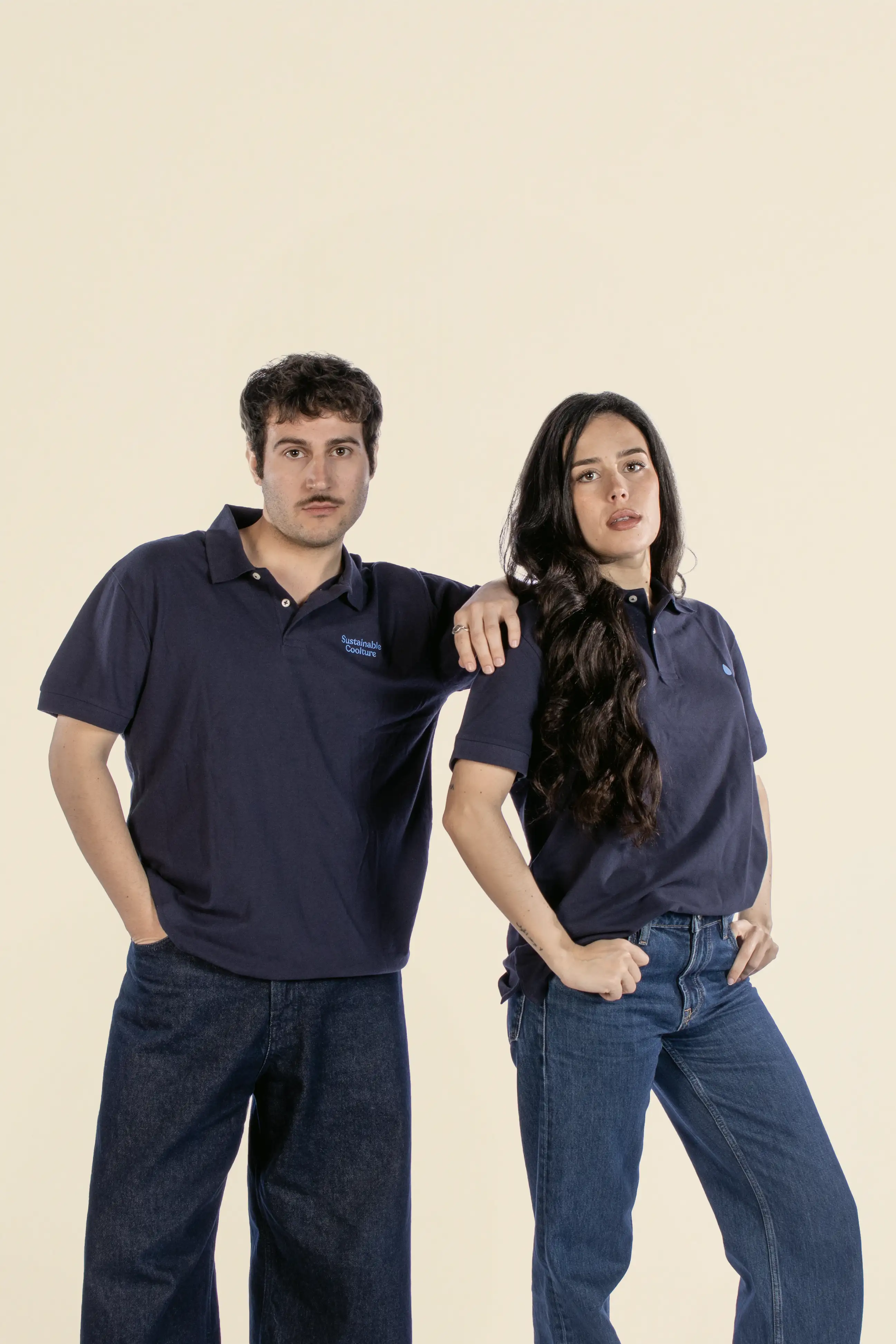 Chico y chica mirando a cámara, llevando vaqueros y dos polos azules personalizados