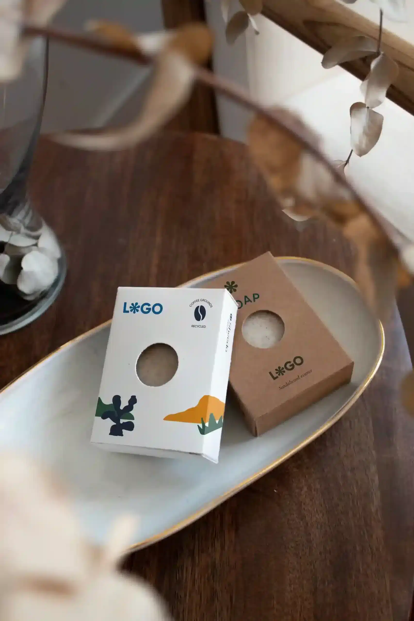 Dos jabones artesanales dentro de sus cajas colocados sobre una bandeja en una mesa de madera