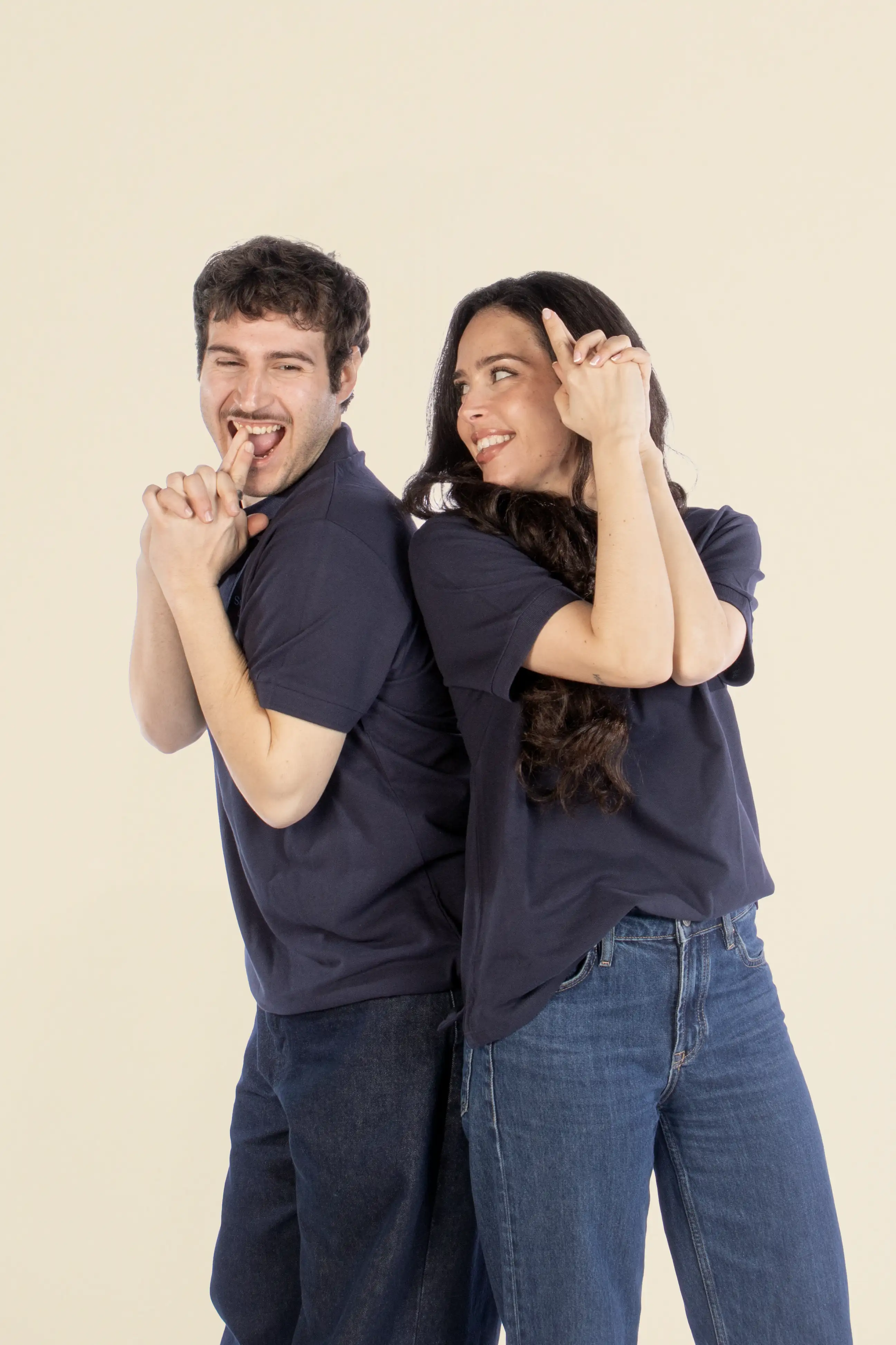 Chico y chica sonriendo, llevando vaqueros y dos polos azules personalizados