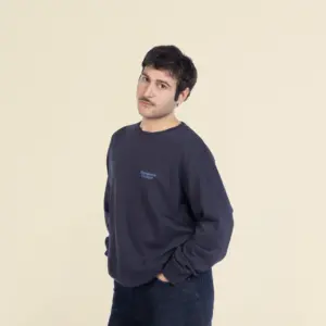 Chico moreno de frente llevando jeans y una sudadera azul personalizada