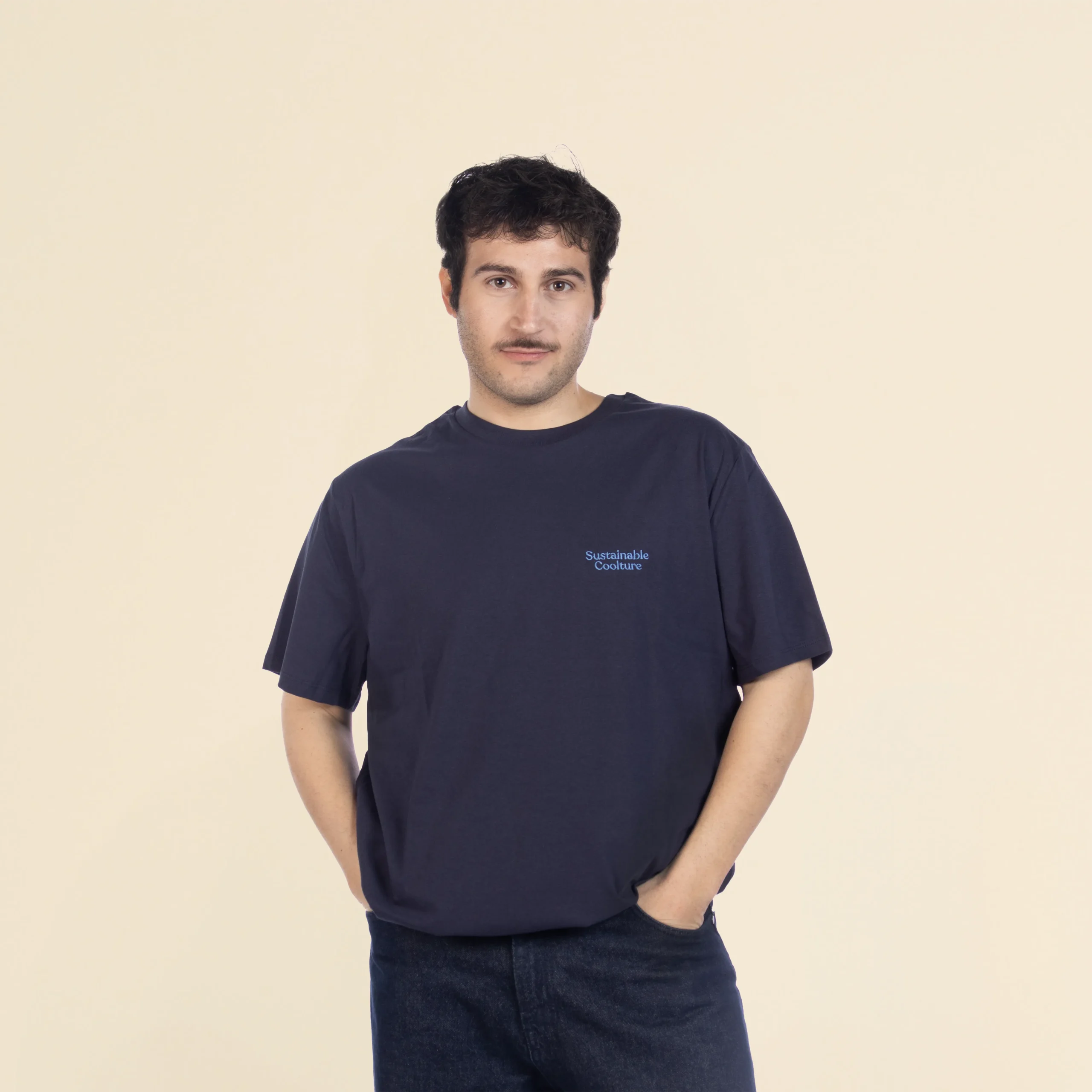 Chico moreno de frente llevando jeans y una camiseta azul marino personalizada