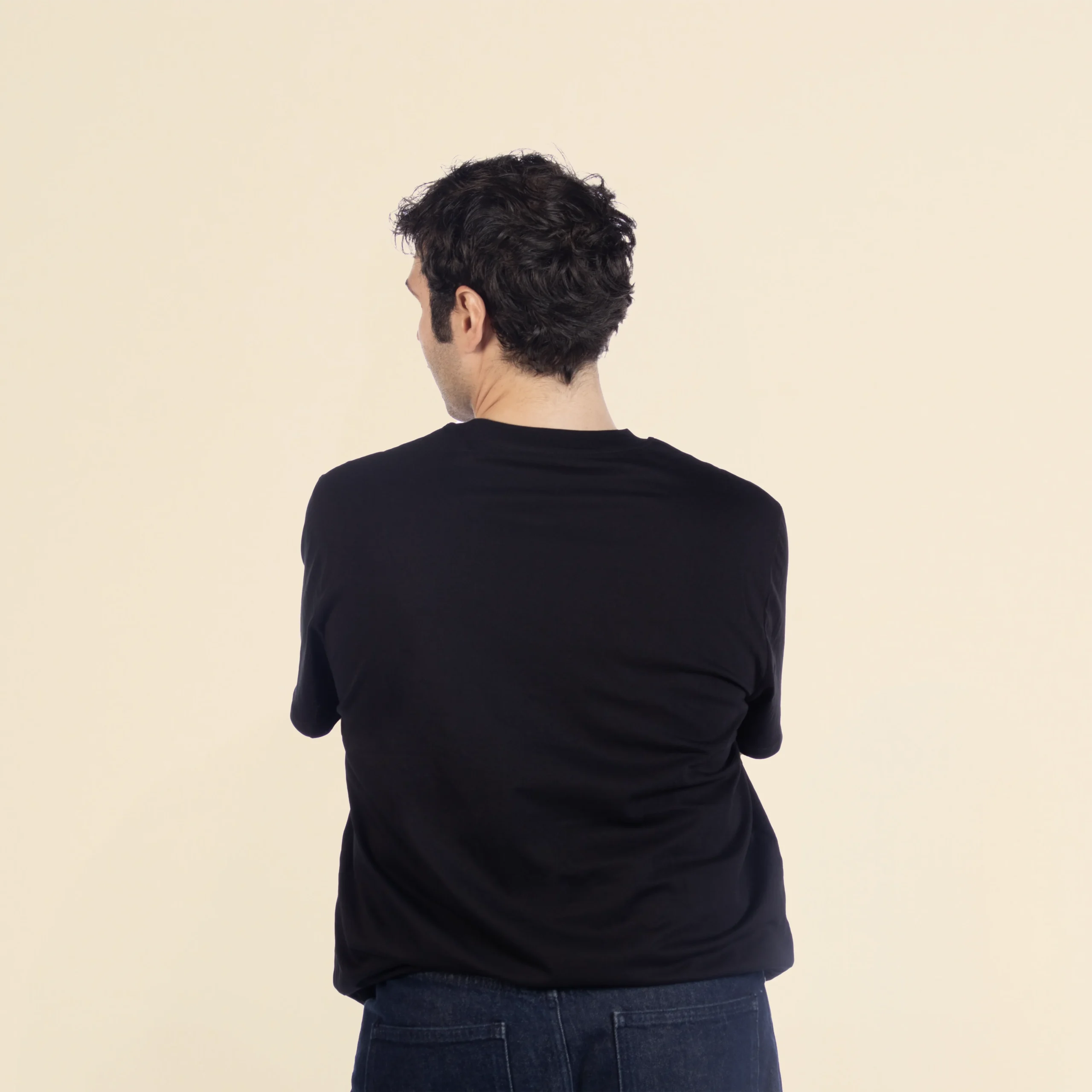 Chico moreno de espaldas llevando jeans y una camiseta de algodón negra