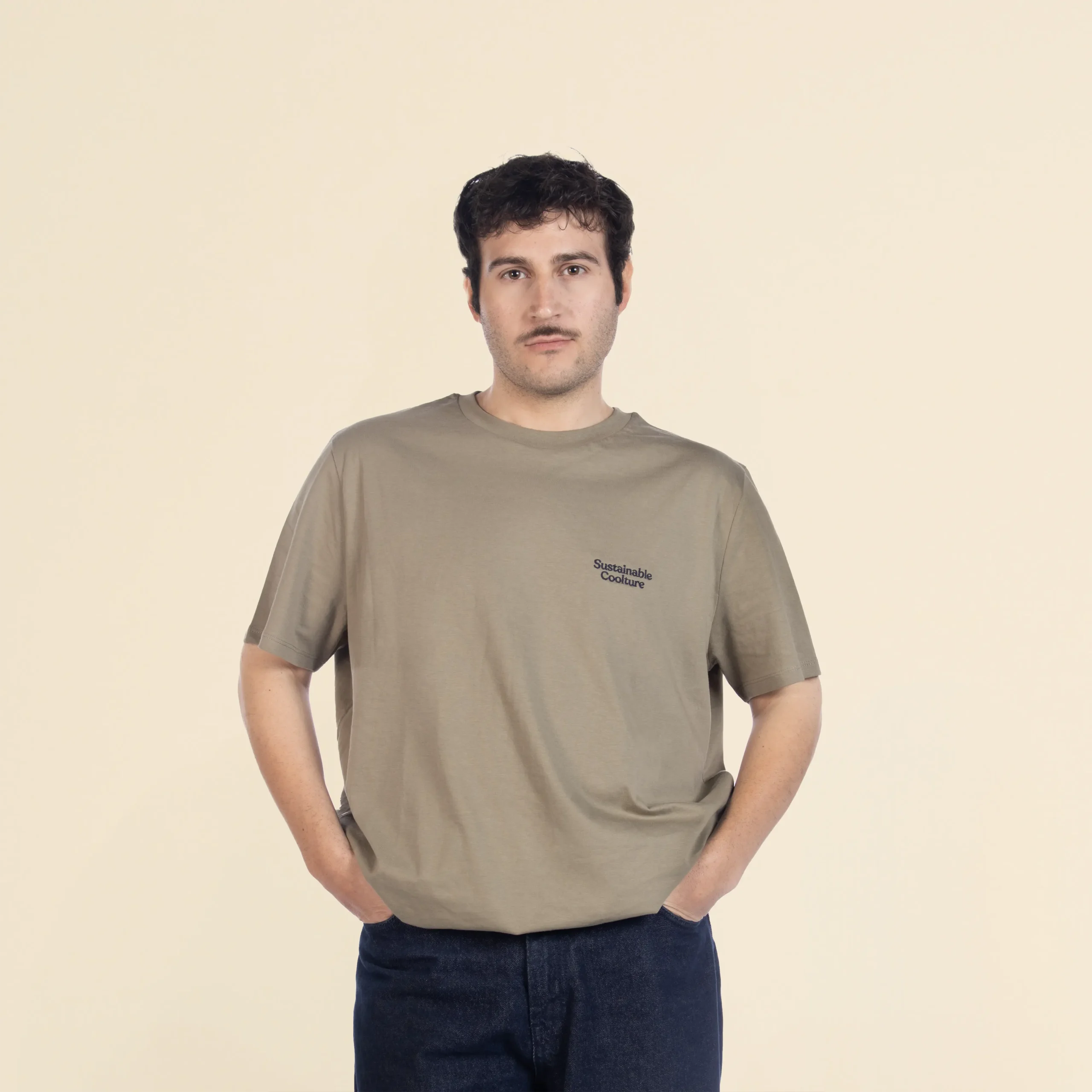 Chico moreno de frente llevando jeans y una camiseta verde personalizada