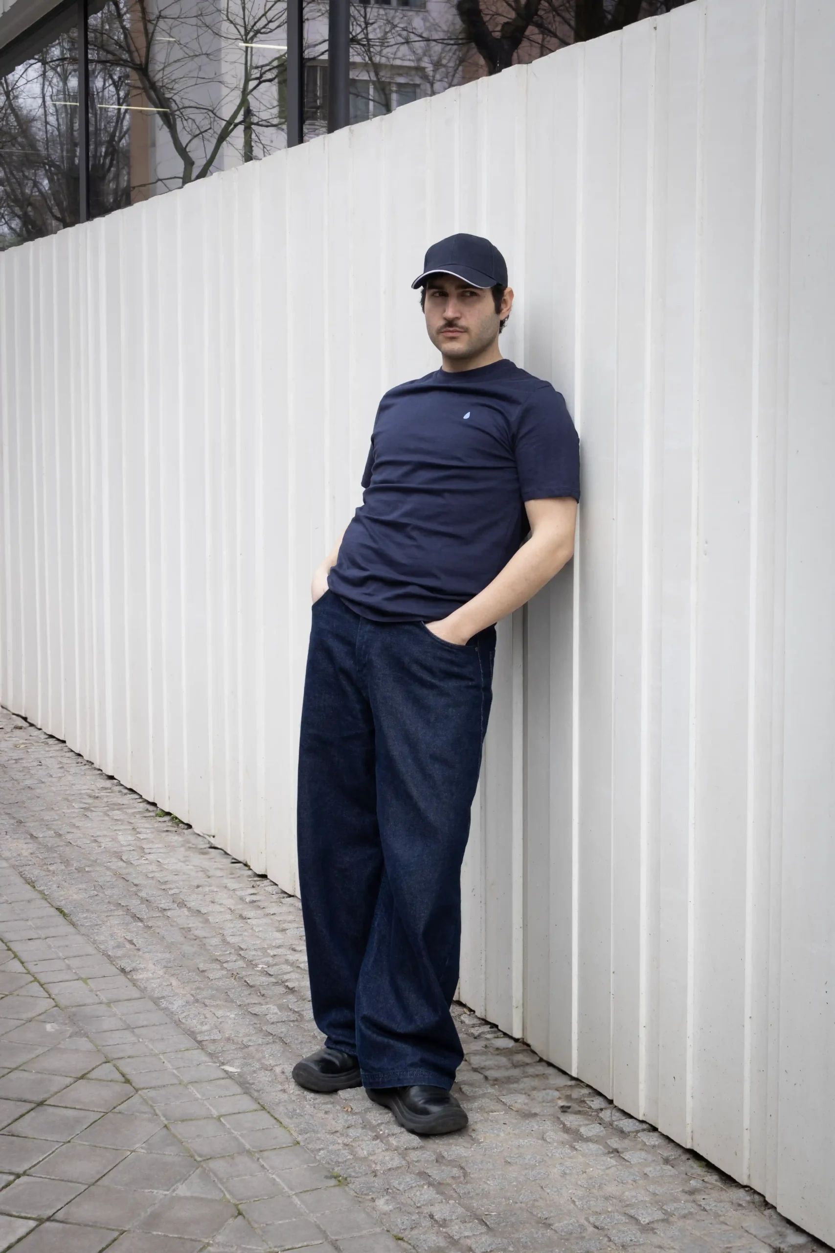 Chico moreno posando en la calle llevando jeans y una camiseta azul marino personalizada