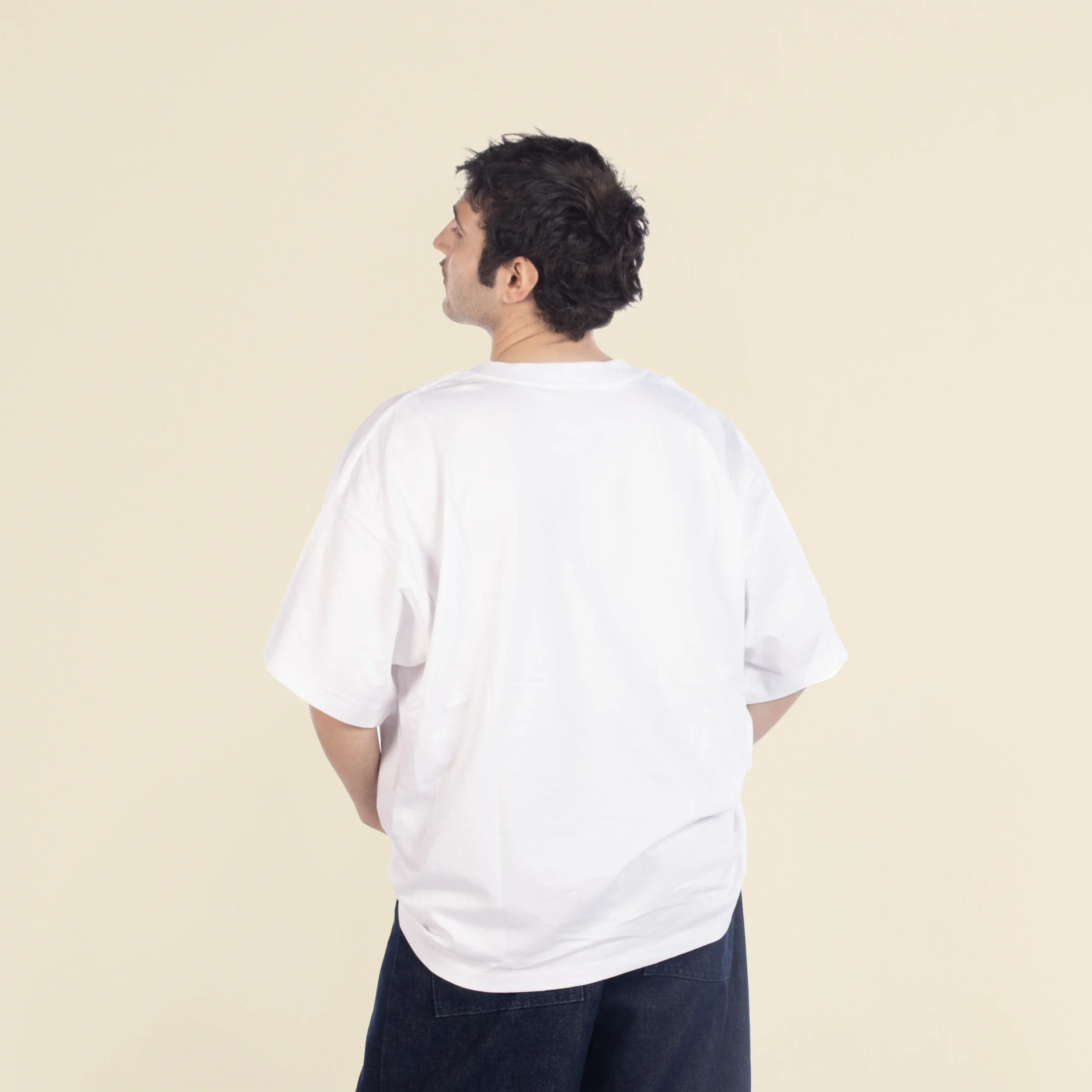 Camiseta oversize VEGA Blanca Chico moreno de espaldas llevando jeans y una camiseta oversize blanca
