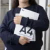 Chica abrazando dos hojas A4 impresas en papel plantable