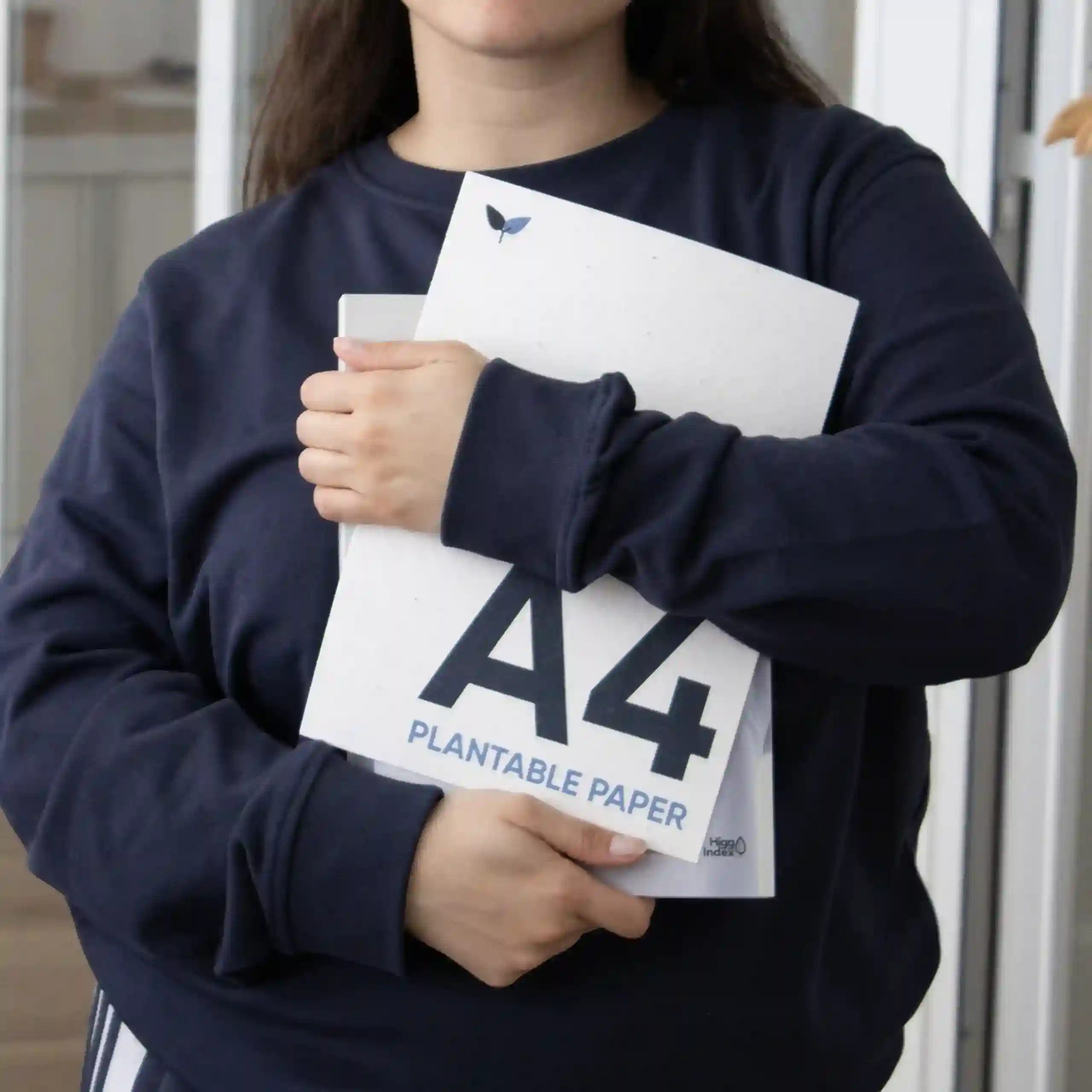 Chica abrazando dos hojas A4 impresas en papel plantable