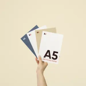 Mano sujetando cuatro tarjetas A5 impresas en papeles ecológicos