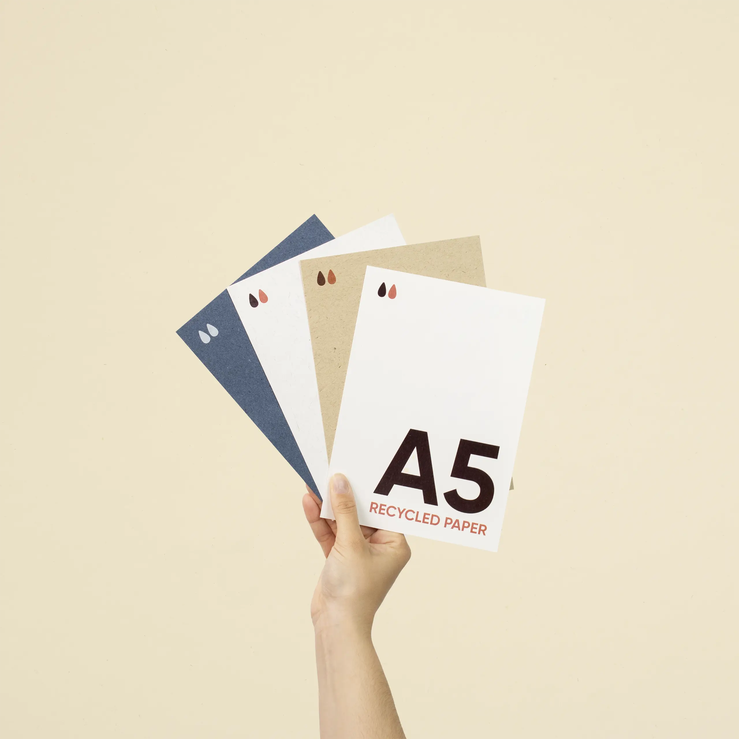 Mano sujetando cuatro tarjetas A5 impresas en papeles ecológicos