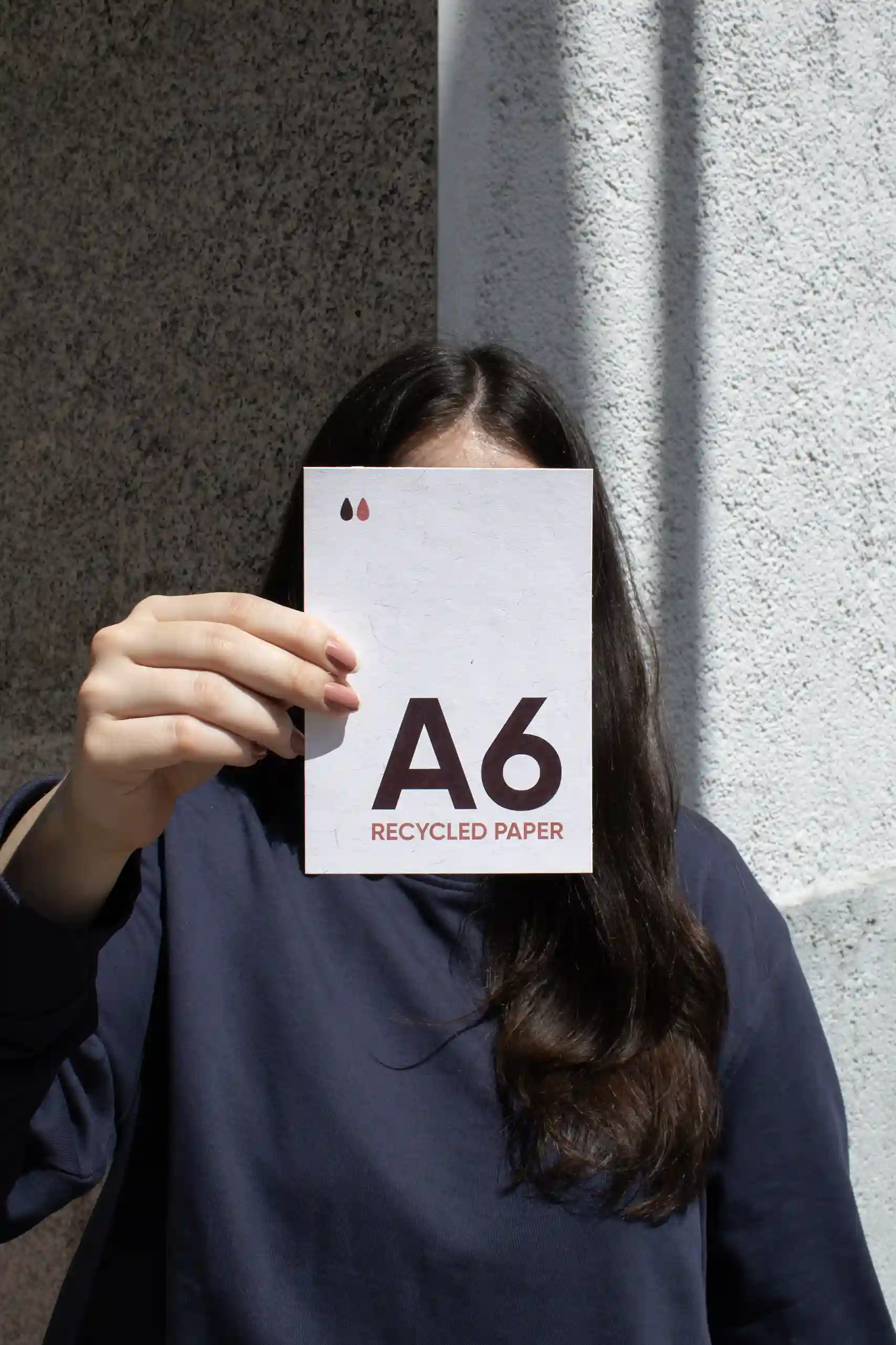 Chica mostrando a cámara una tarjeta A6 impresa en papel ecológico