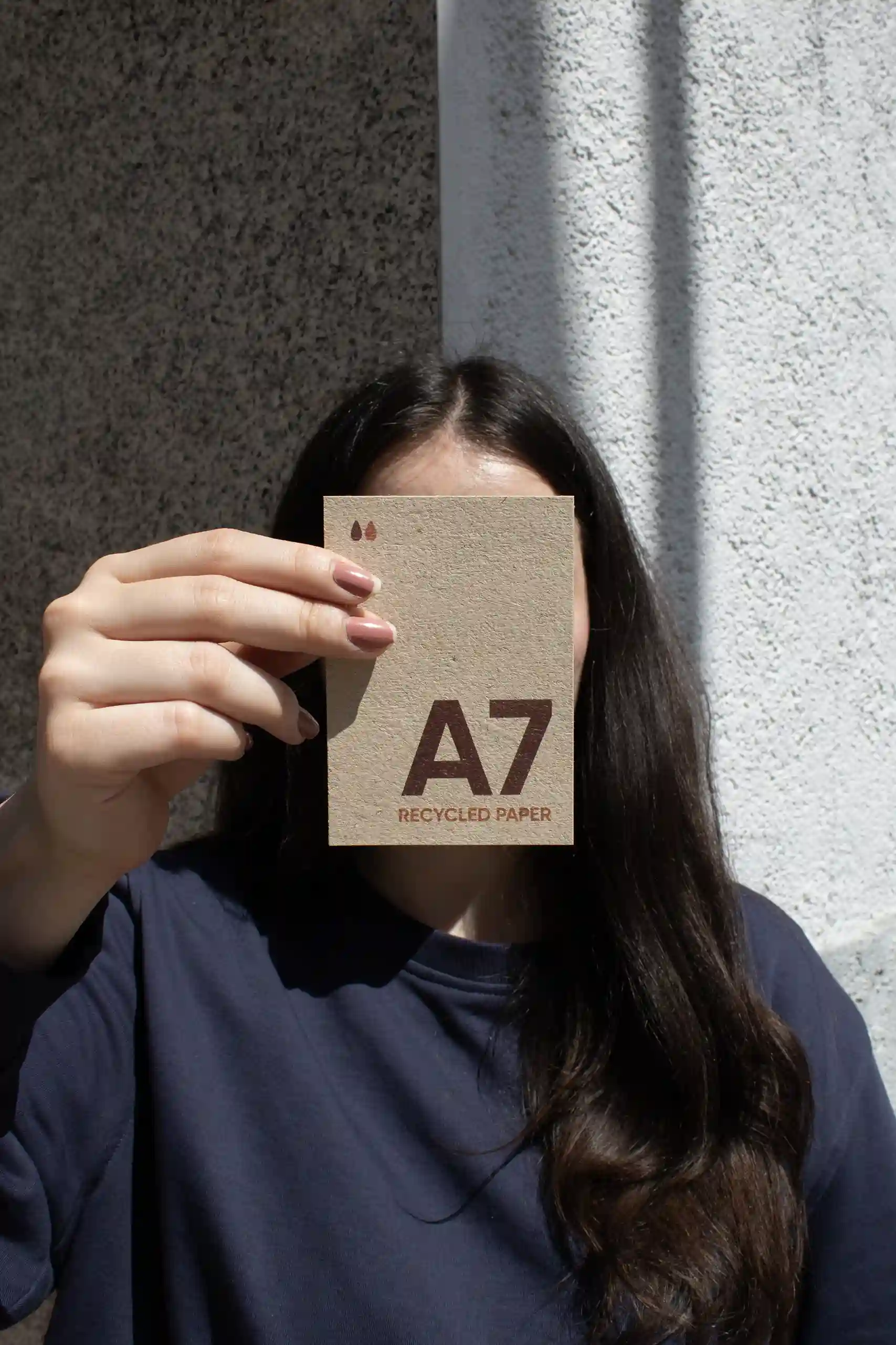 Chica mostrando a cámara una tarjeta A7 impresa en papel ecológico