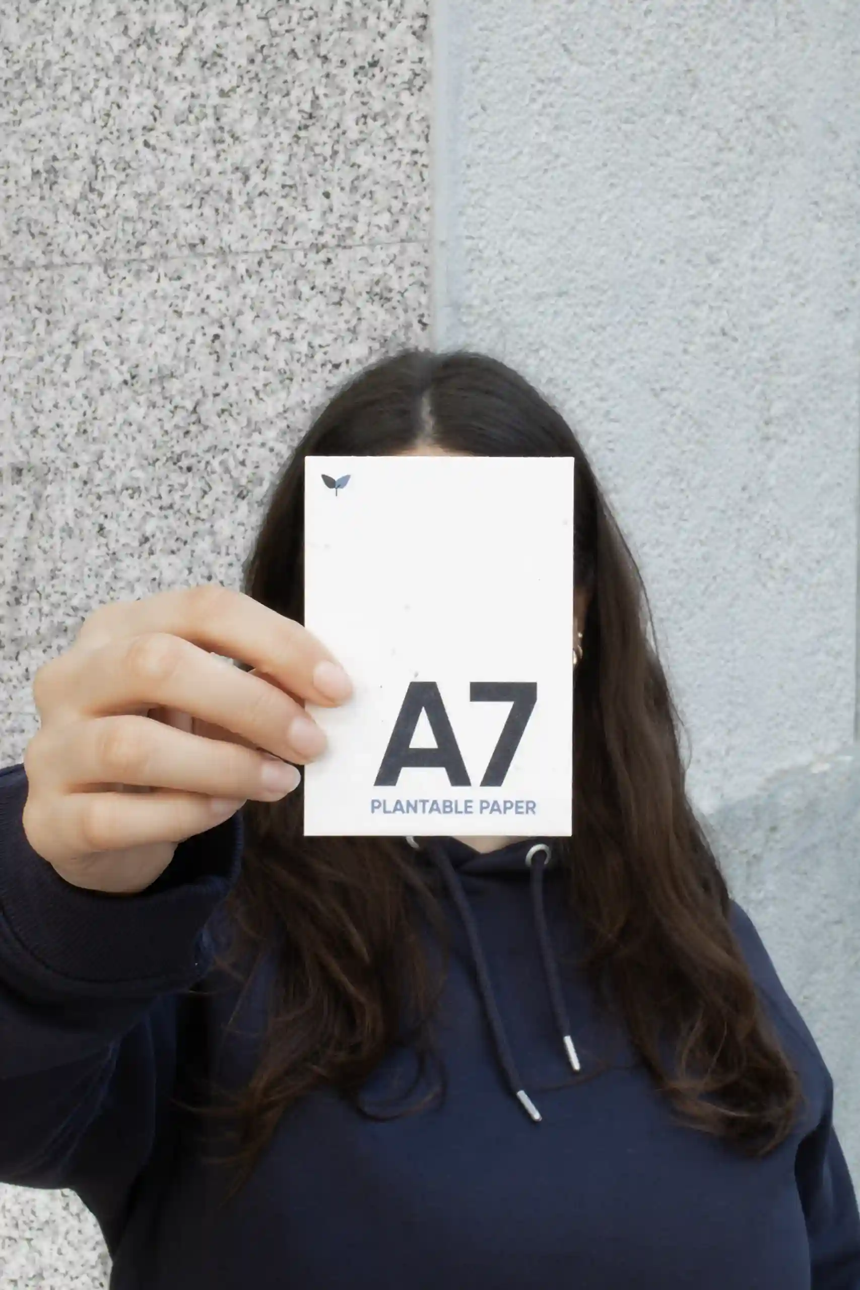 Chica mostrando a cámara una tarjeta A7 impresa en papel plantable