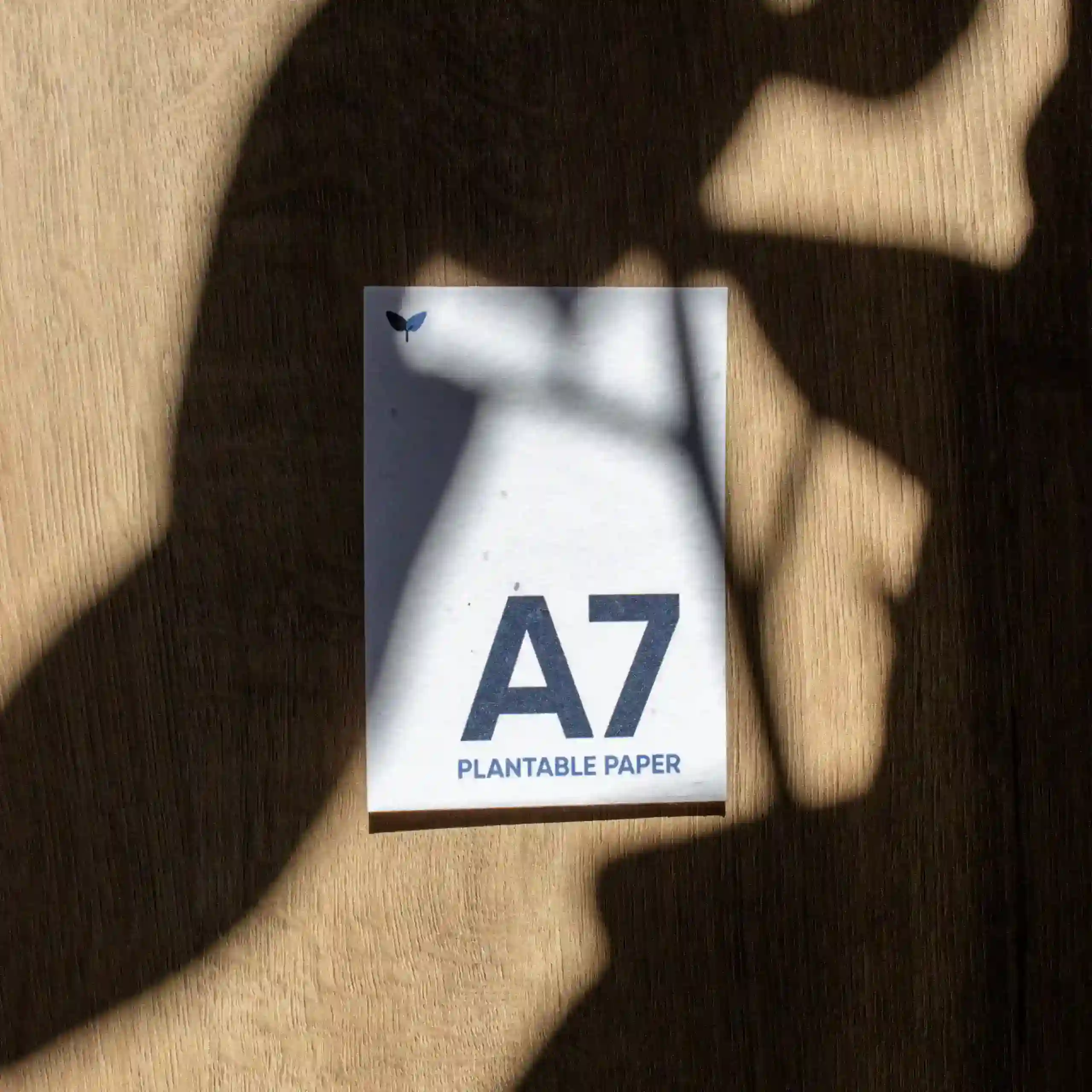 Tarjeta A7 impresa en papel plantable sobre una superficie de madera con sombras