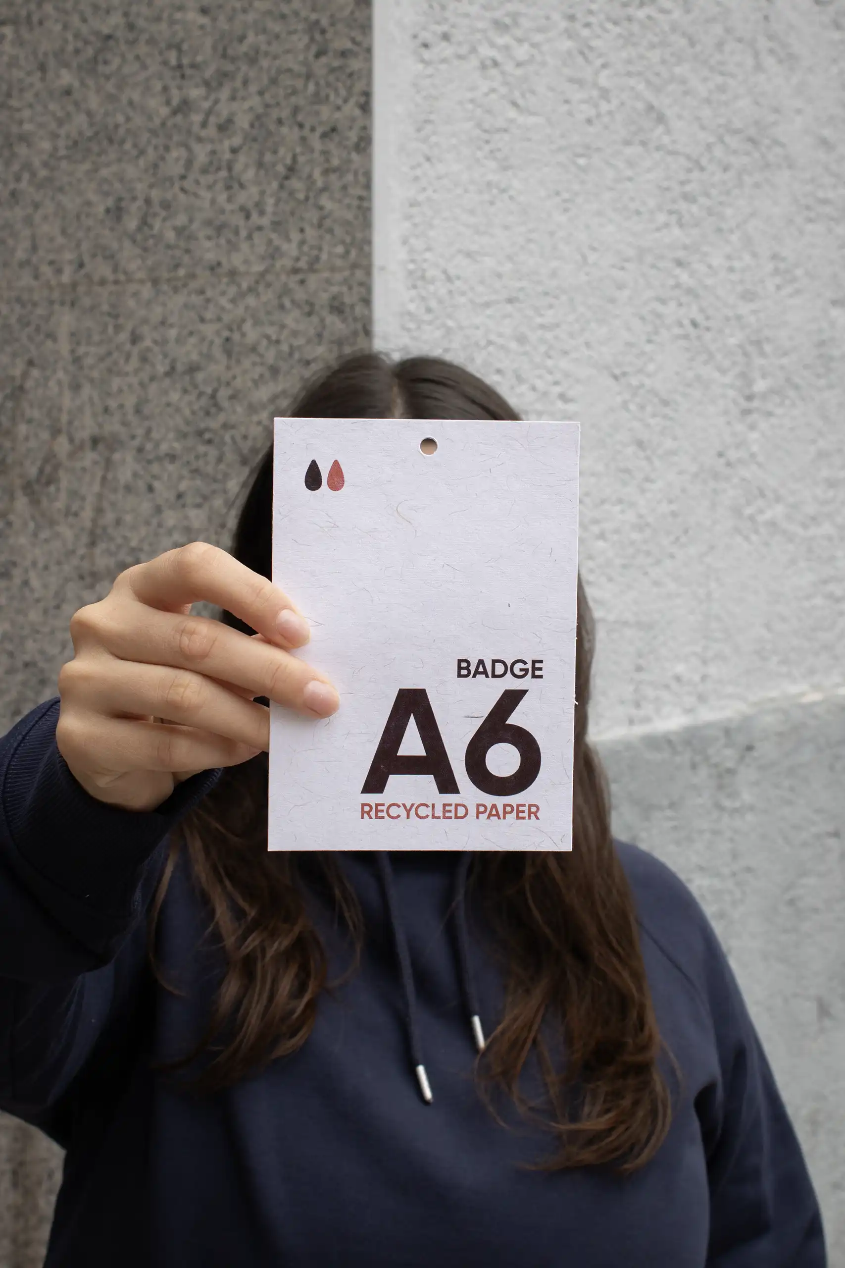 Chica mostrando a cámara una acreditación A6 impresa en papel ecológico