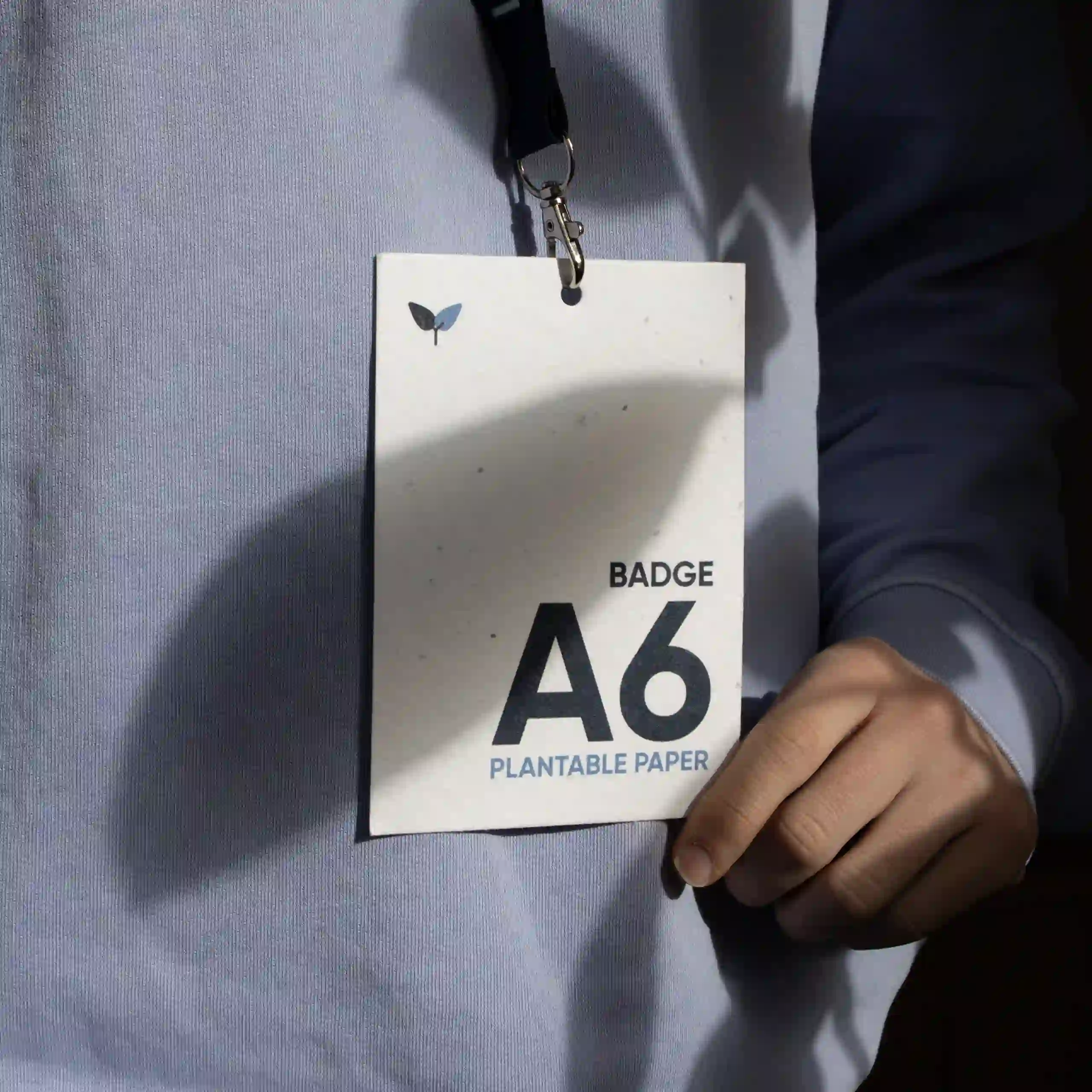 Acreditación A6 impresa en papel plantable con lanyard colgada del cuello de una persona