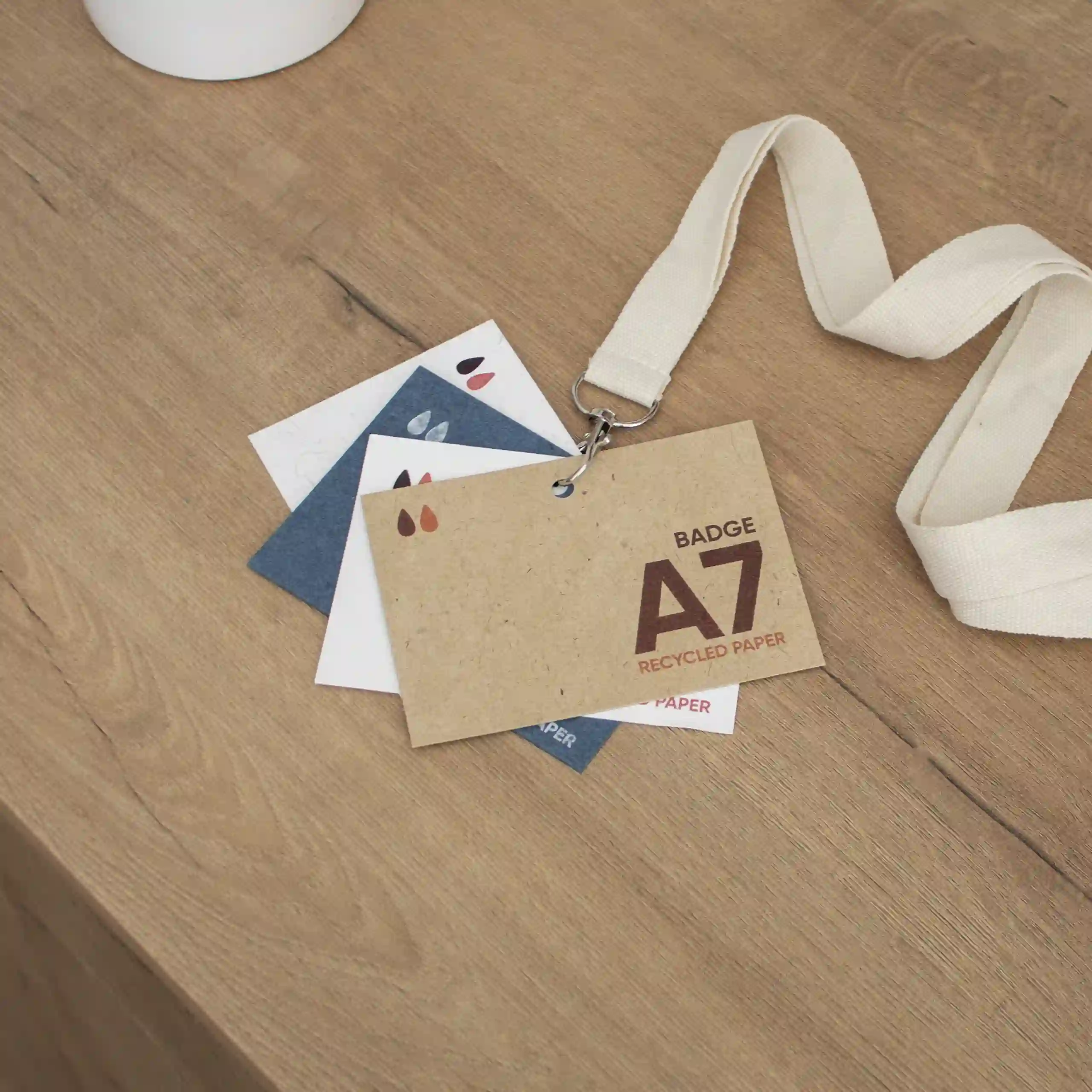 Cuatro acreditaciones A7 impresas en papeles ecológicos sobre superficie de madera