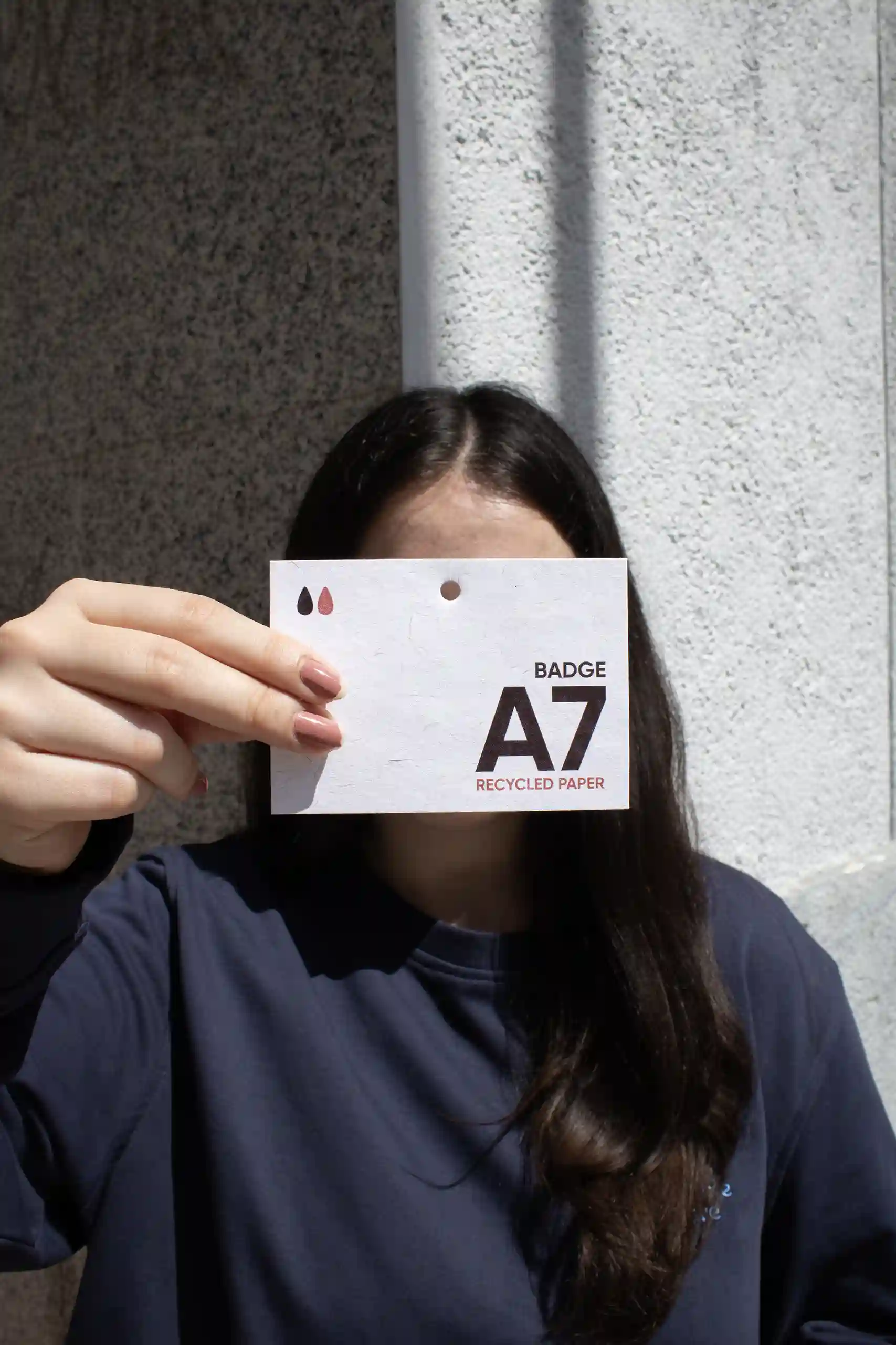Chica mostrando a cámara una acreditación A7 impresa en papel ecológico