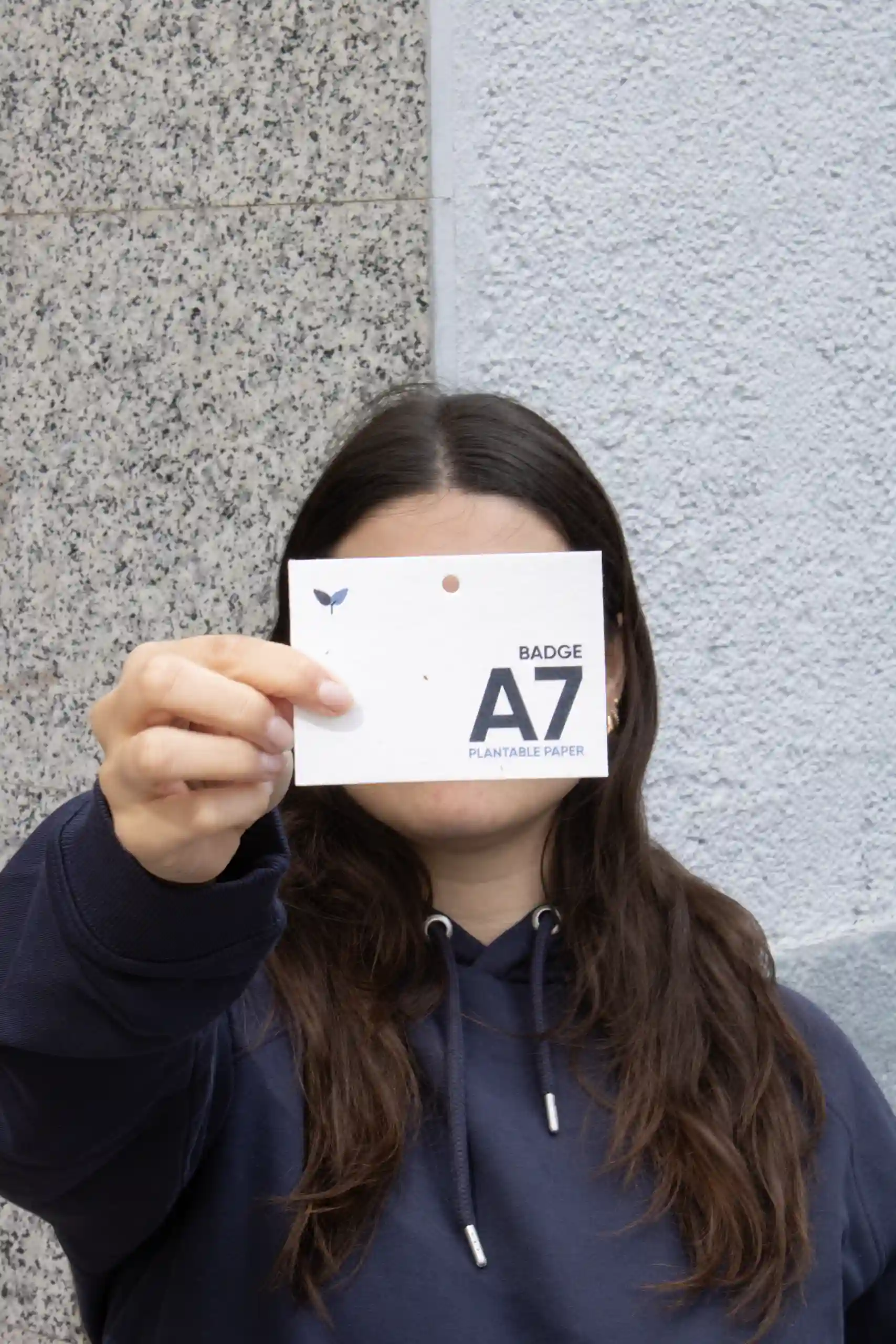 Chica mostrando a cámara una acreditación plantable A7 impresa en papel plantable