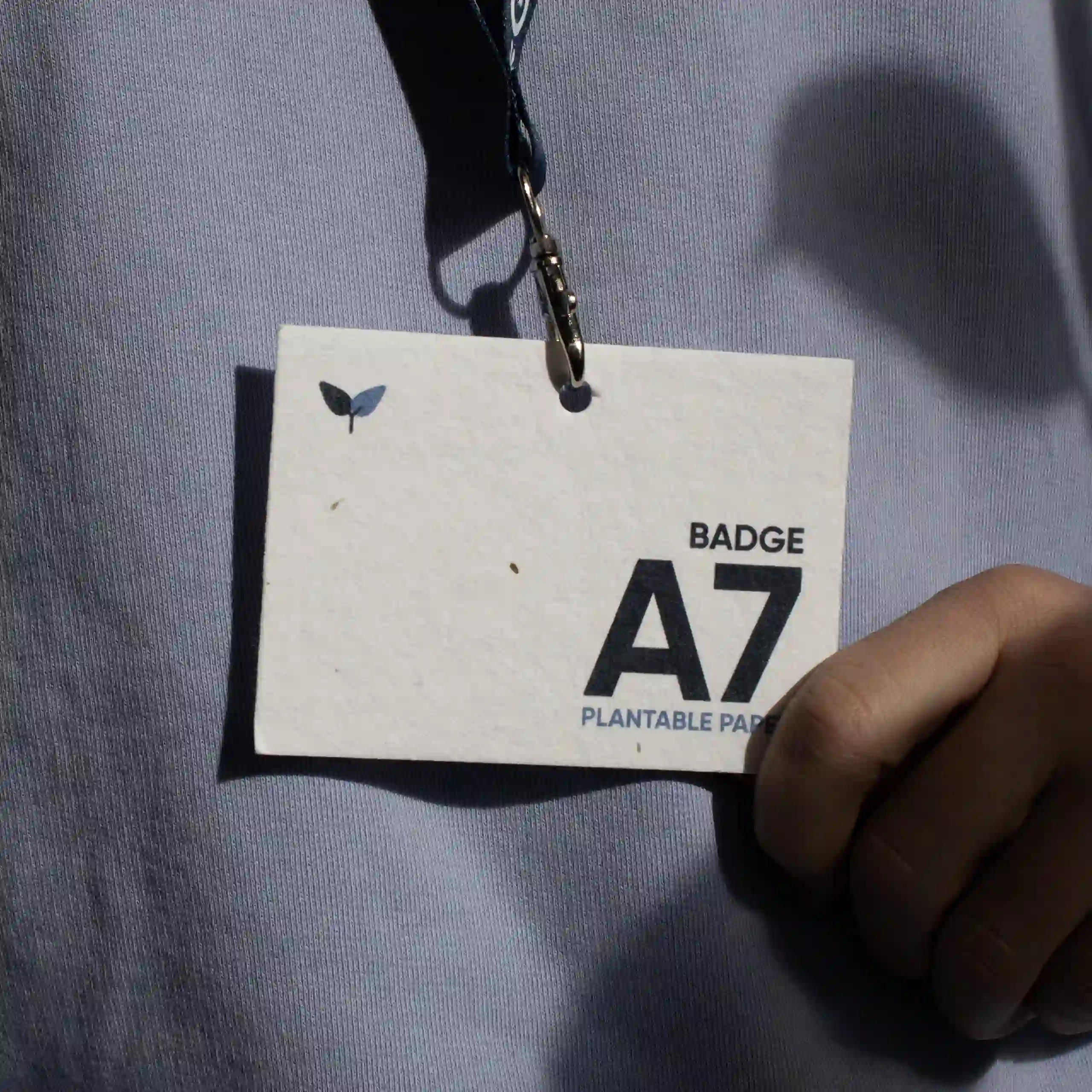Acreditación A7 impresa en papel plantable con lanyard colgada del cuello de una persona
