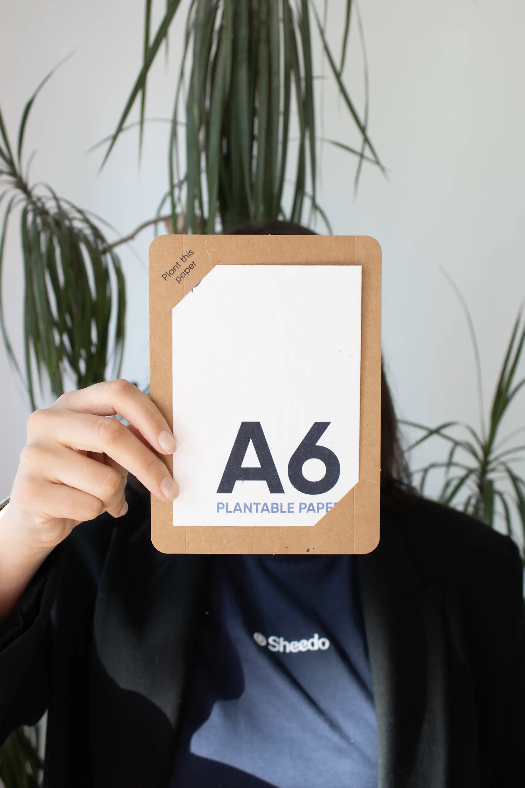 Chica mostrando a cámara una tarjeta A6 impresa en papel plantable dentro de una funda en cartón kraft