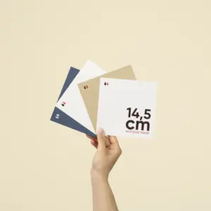 Mano sujetando cuatro tarjetas cuadradas impresas en papel ecológico