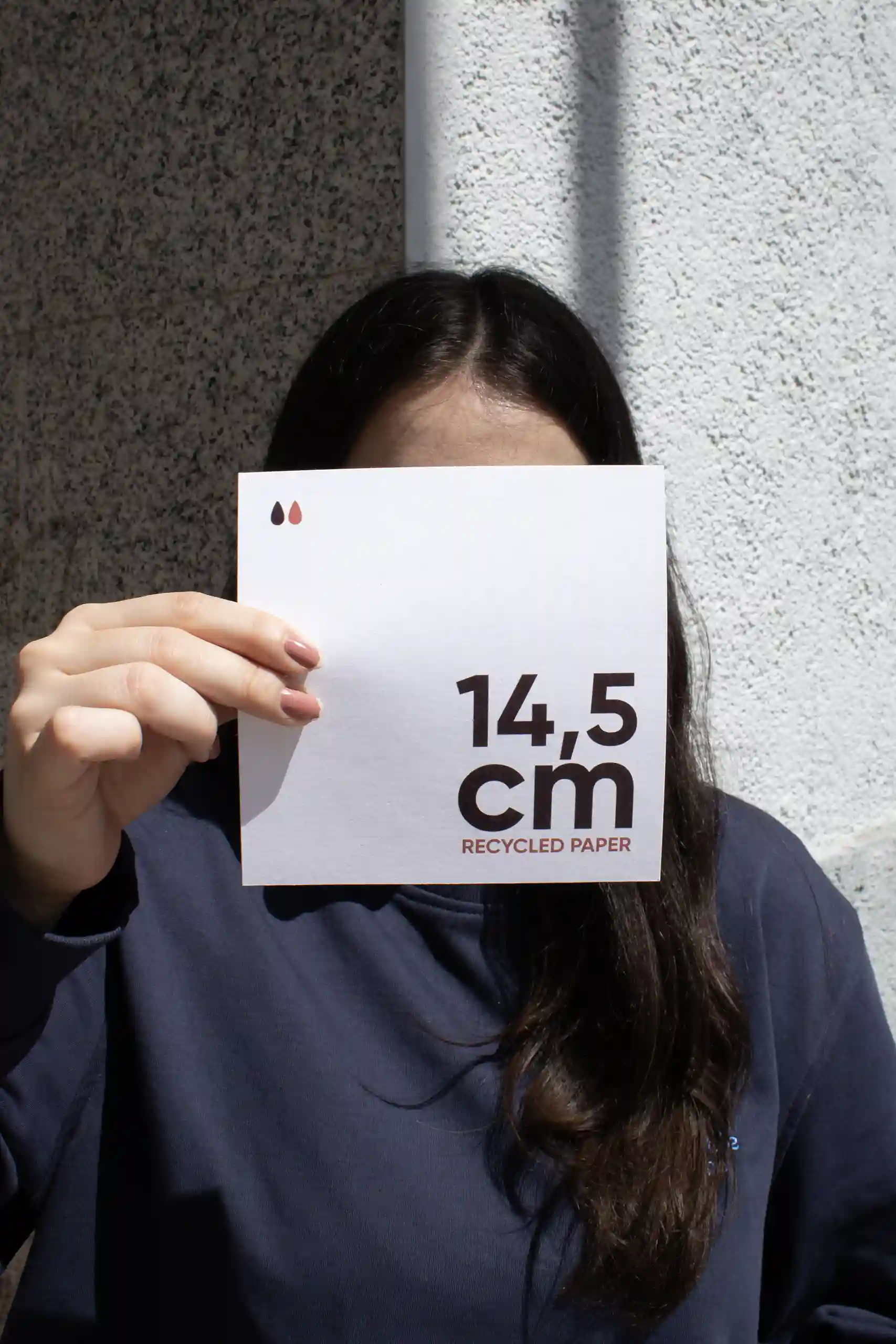 Chica mostrando a cámara una tarjeta cuadrada impresa en papel ecológico