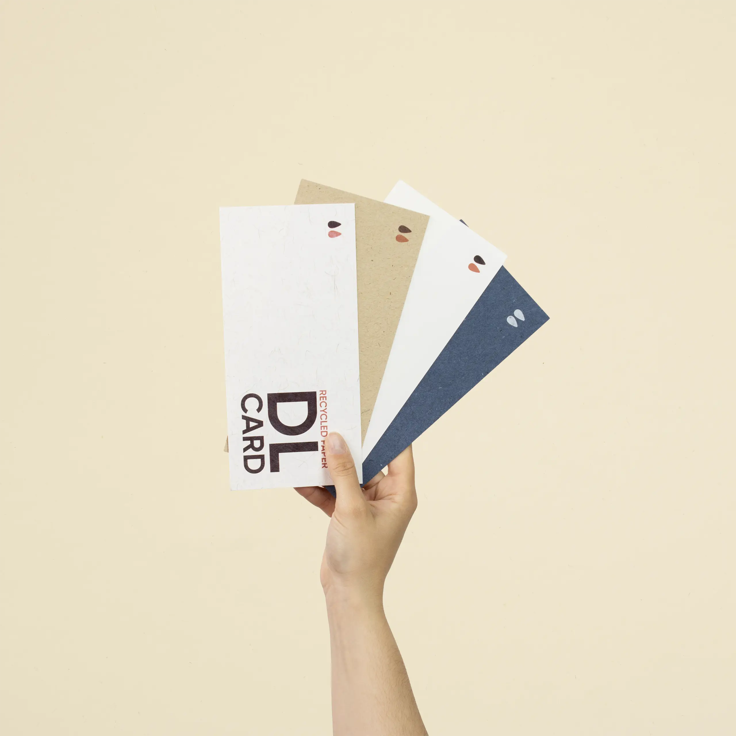 Mano sujetando cuatro tarjetas DL impresas en papel ecológico
