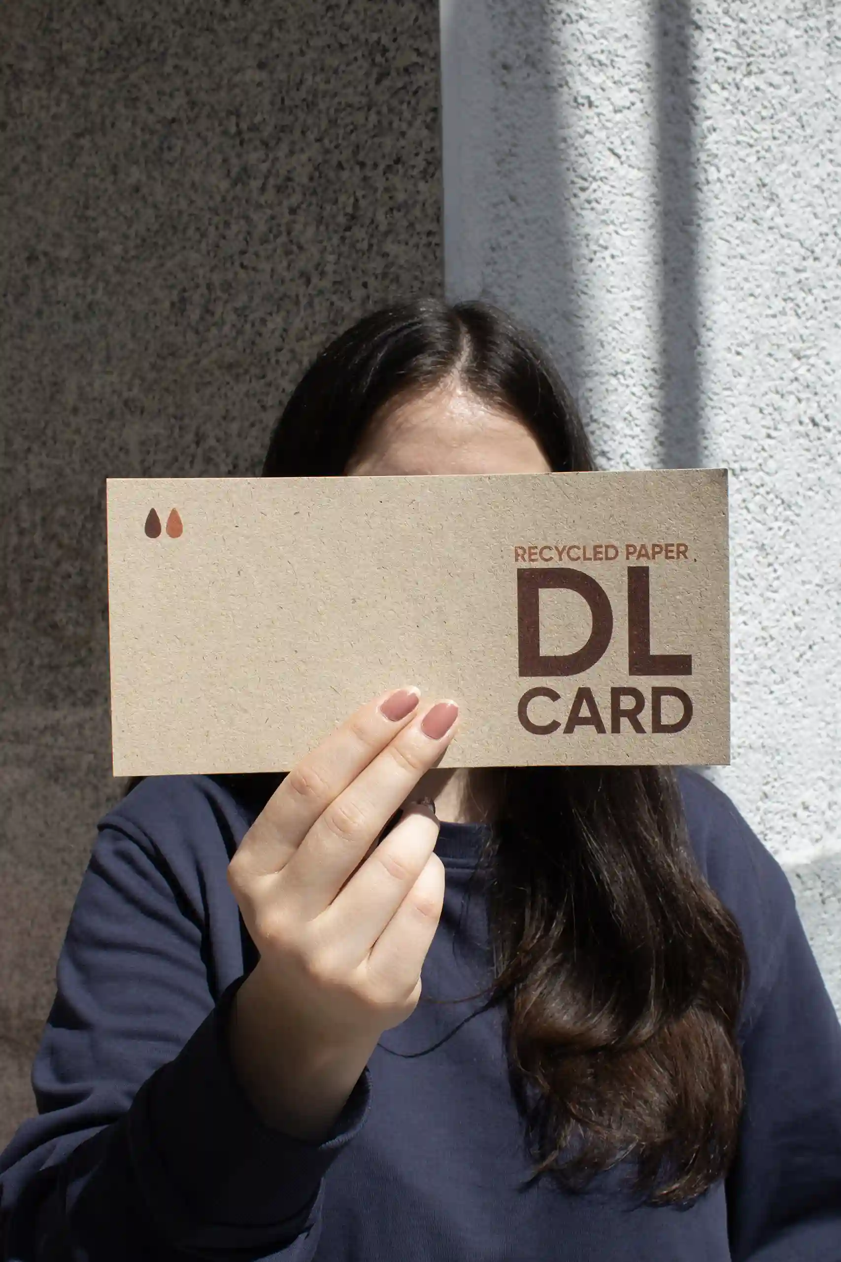 Chica mostrando a cámara una tarjeta DL impresa en papel ecológico