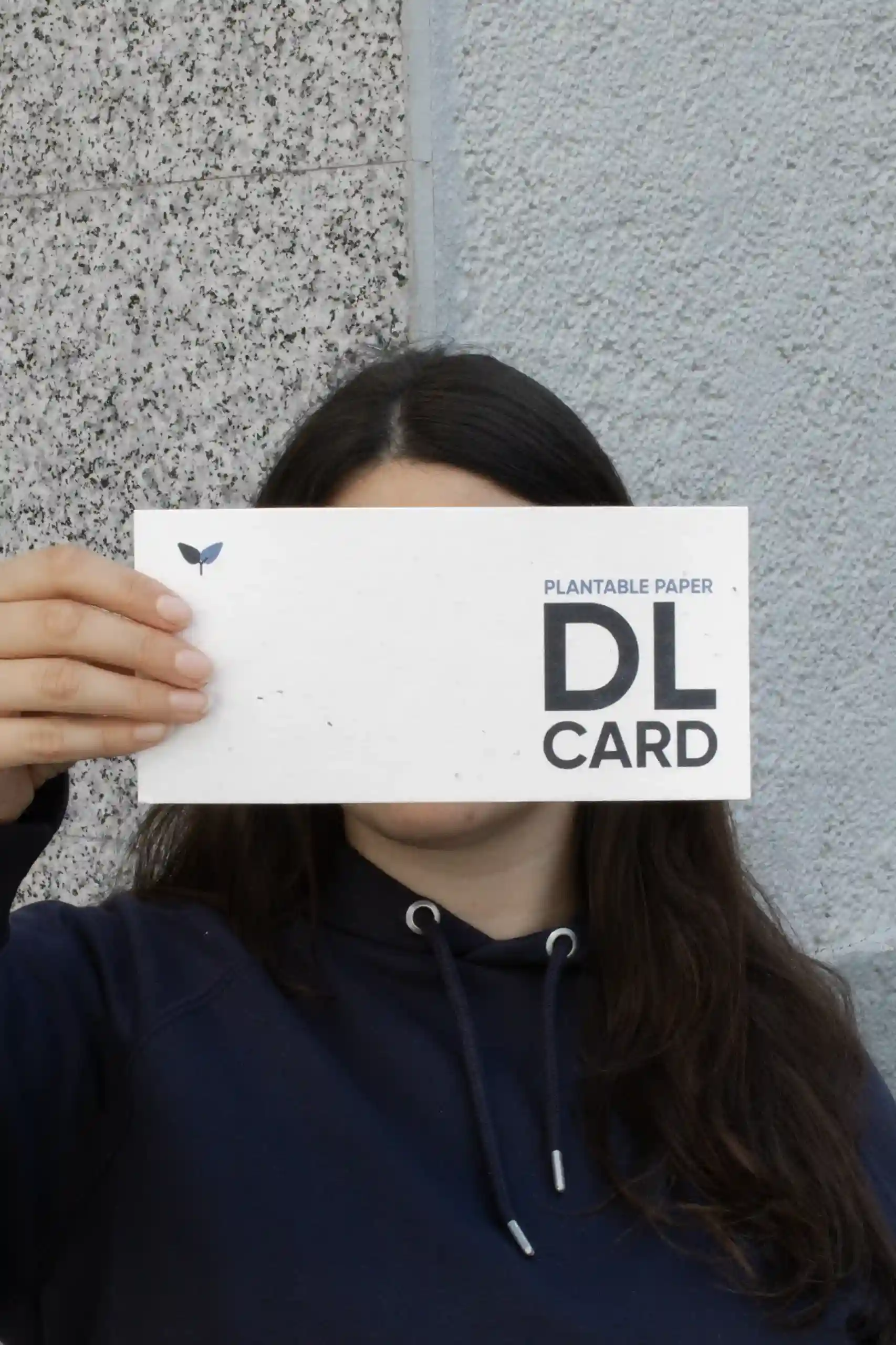 Chica mostrando a cámara una tarjeta DL impresa en papel plantable