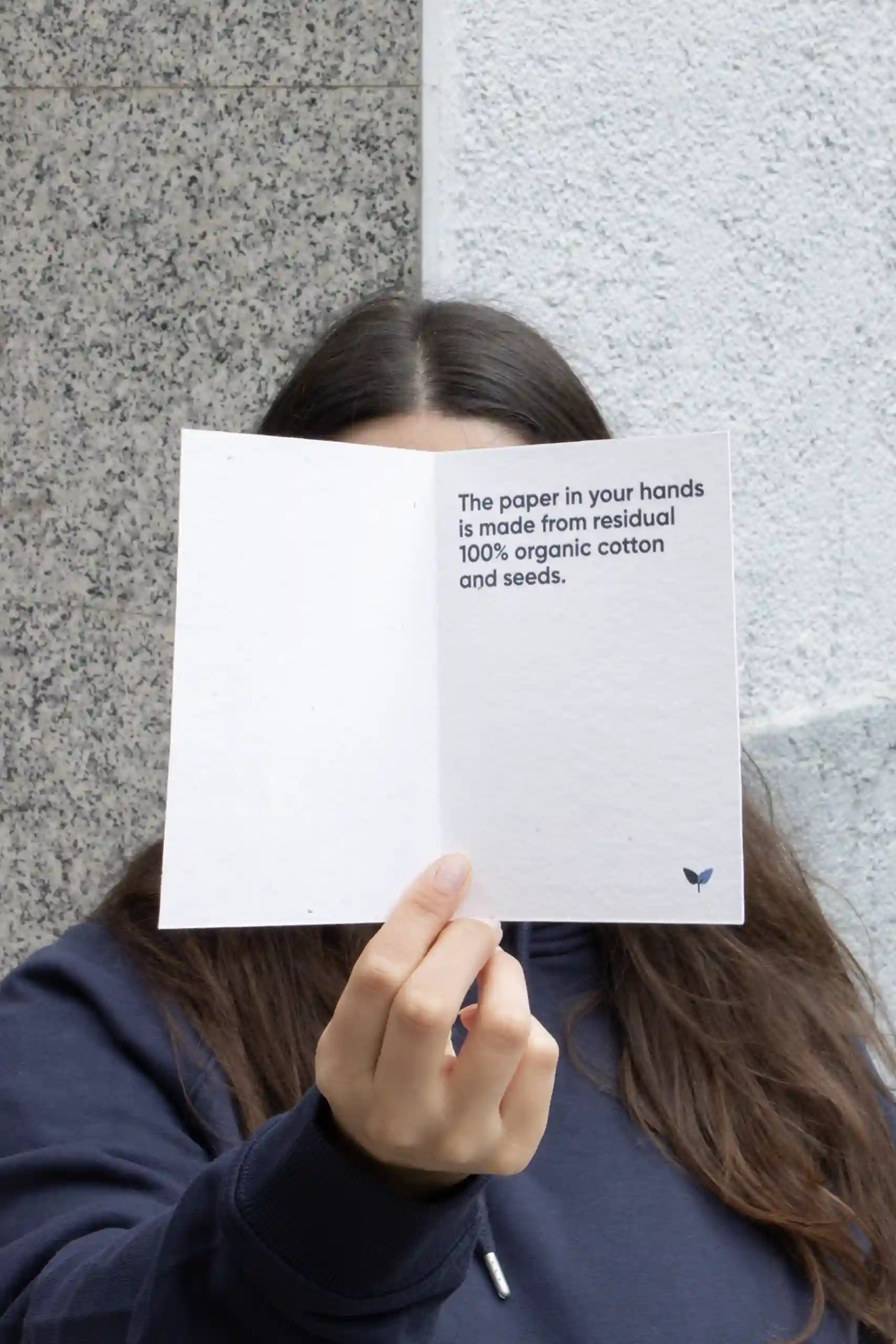 Chica mostrando a cámara un díptico A6 impreso en papel plantable