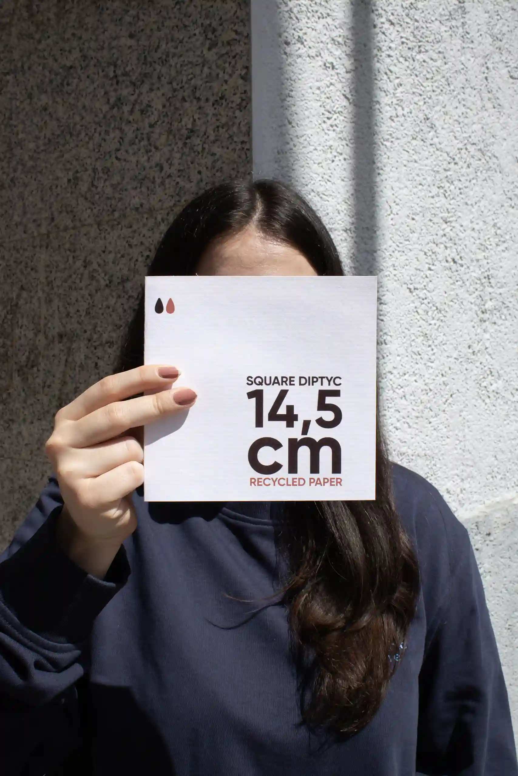 Chica mostrando a cámara un díptico cuadrado impreso en papel ecológico