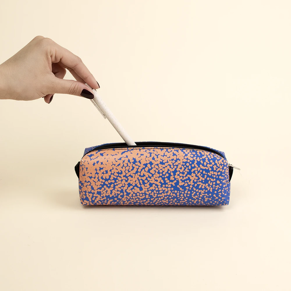 Mano metiendo un boli blanco en un estuche de lona reciclada