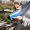 Manos abriendo la cremallera de un estuche de lona reciclada con la ciudad de fondo