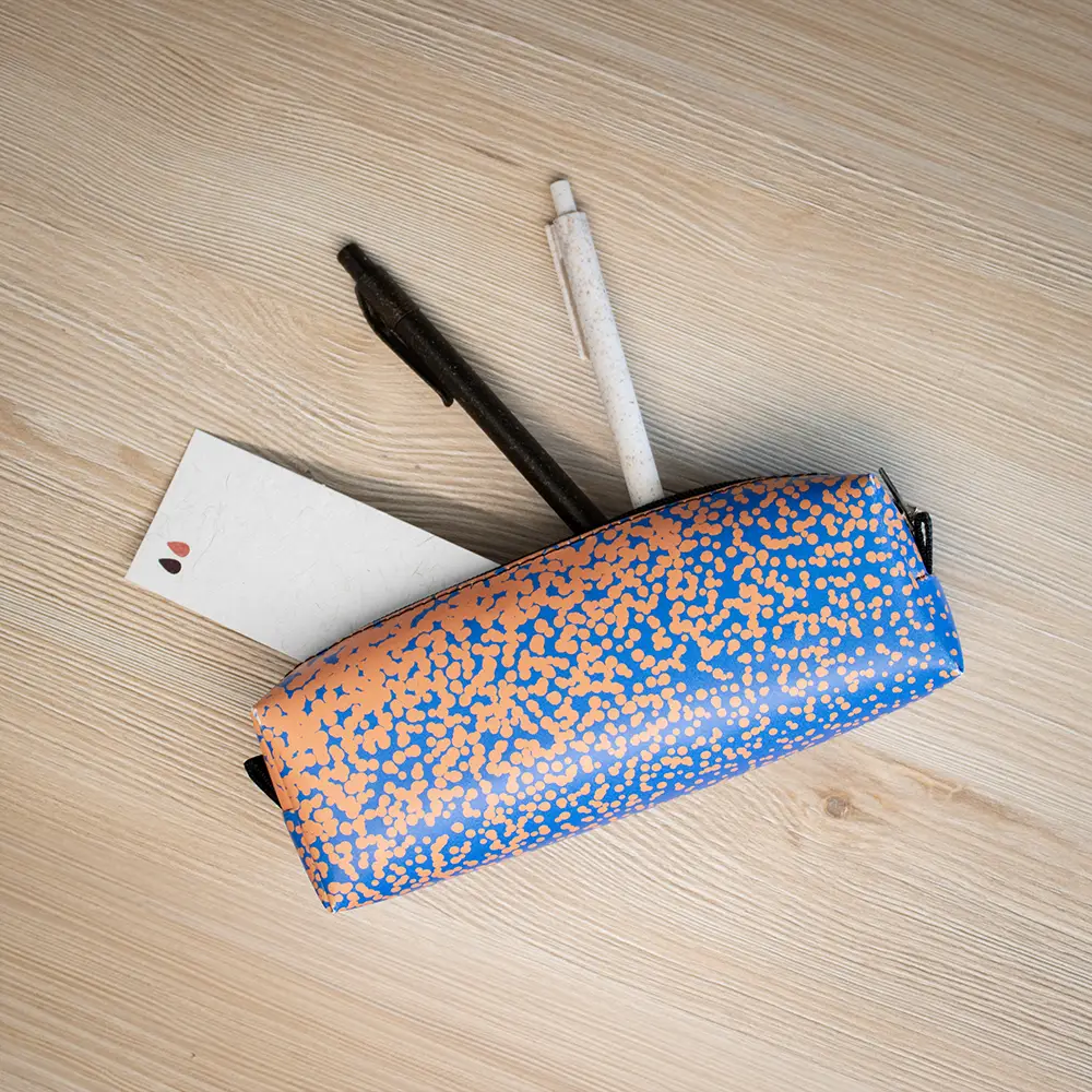 Estuche de lona reciclada con dos bolis y un marcapáginas sobre una superficie de madera