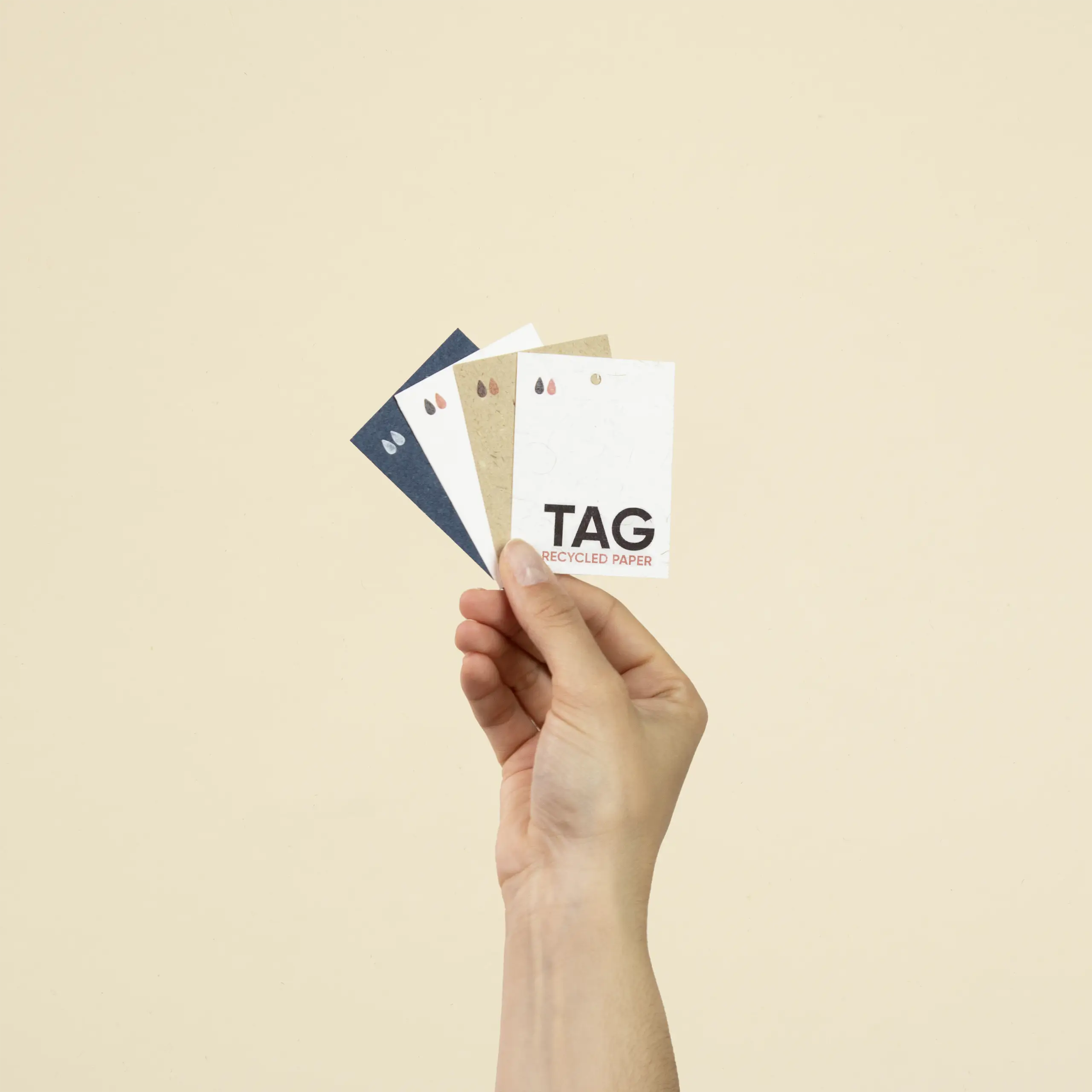 Mano sujetando cuatro etiquetas impresas en papeles ecológicos