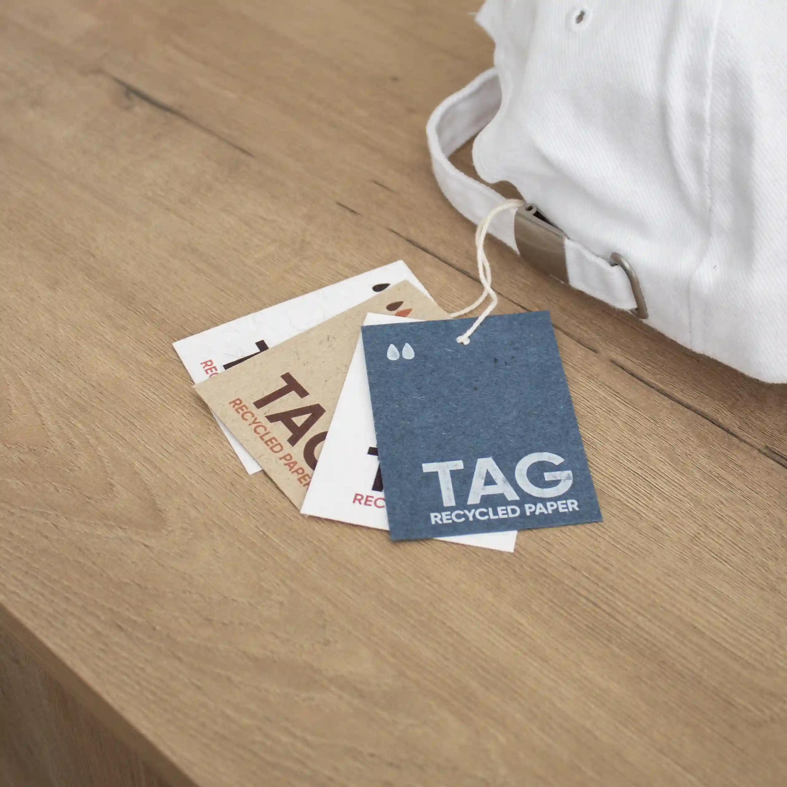 Etiquetas papel ecológico cuatro tarjetas de visita impresas en papeles ecológicos colgadas de una bolsa blanca sobre una superficie de madera